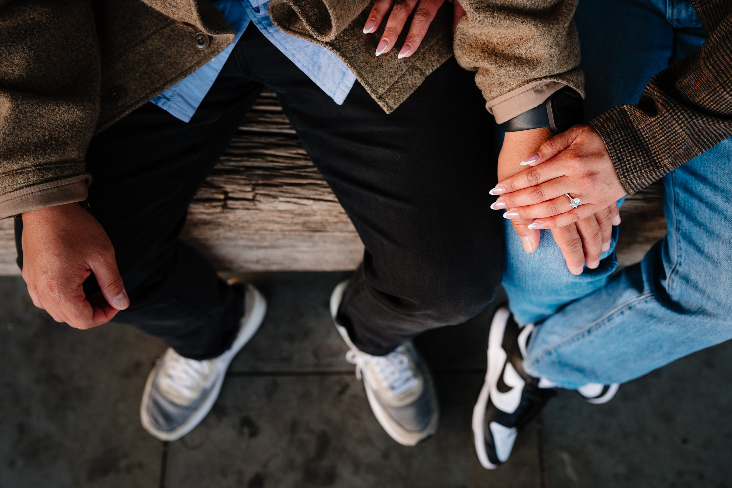 A couple sat on a bench hands together
