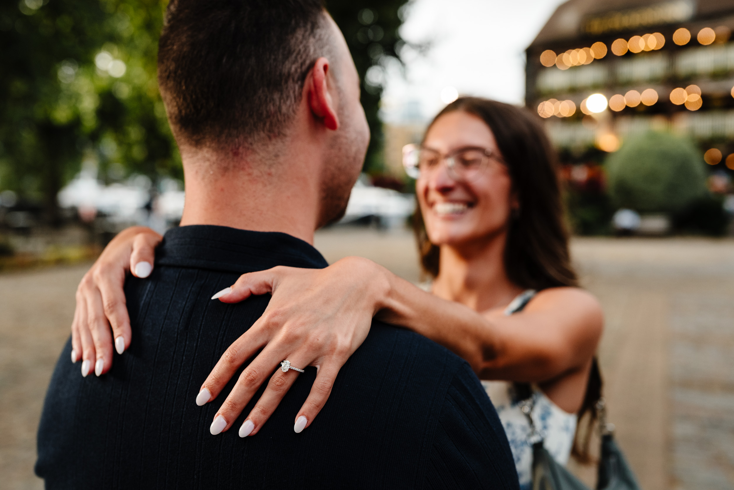 lady's hand on gents back with engagement ring