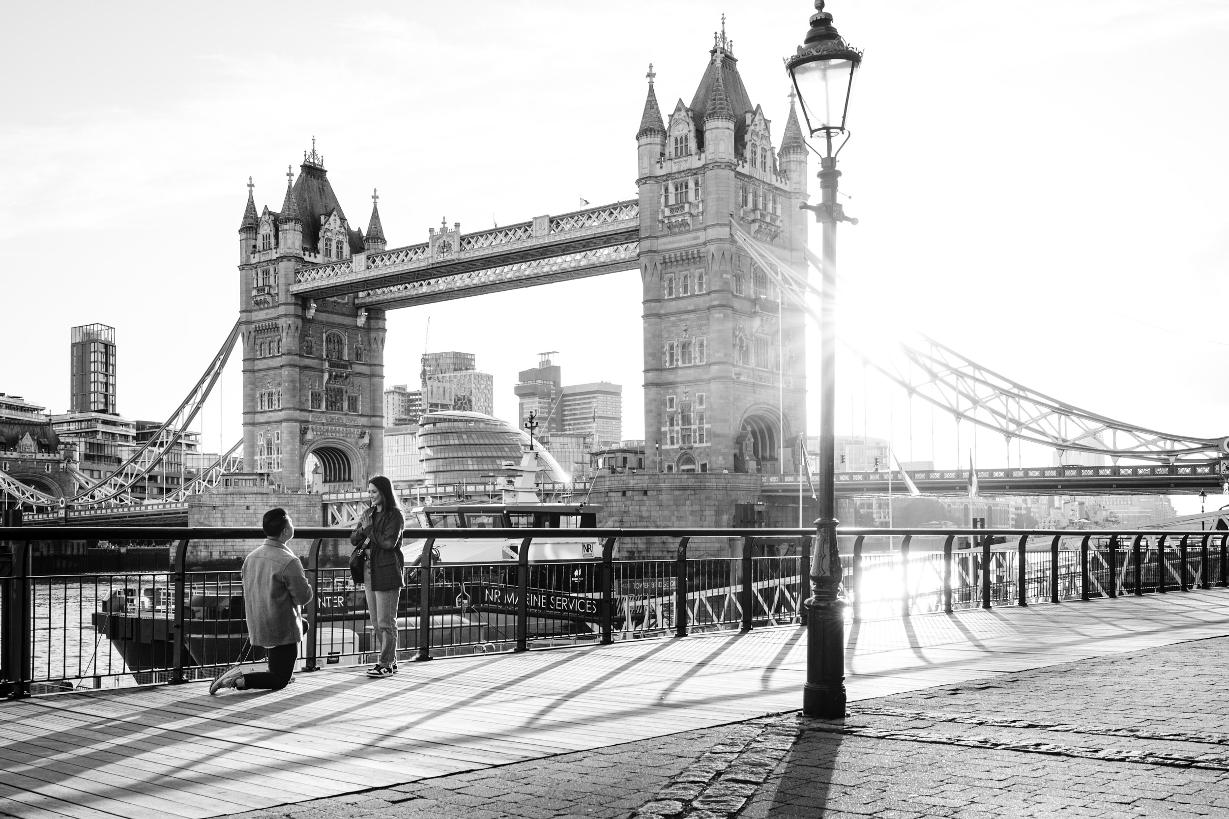 Guy proposes to his girlfriend with Tower Bridge behind them