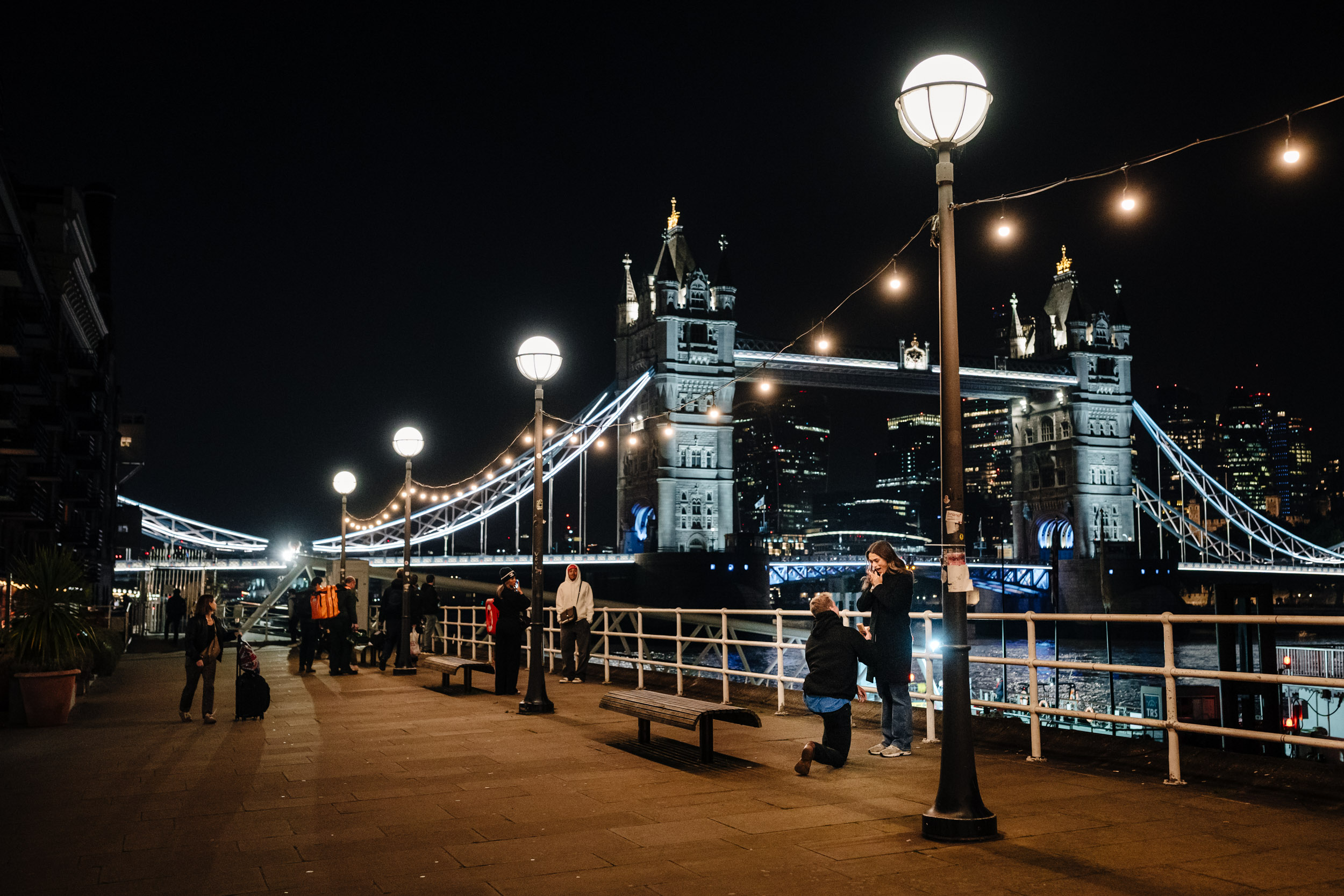 a guy proposing to his girlfriend at Tower Bridge at night