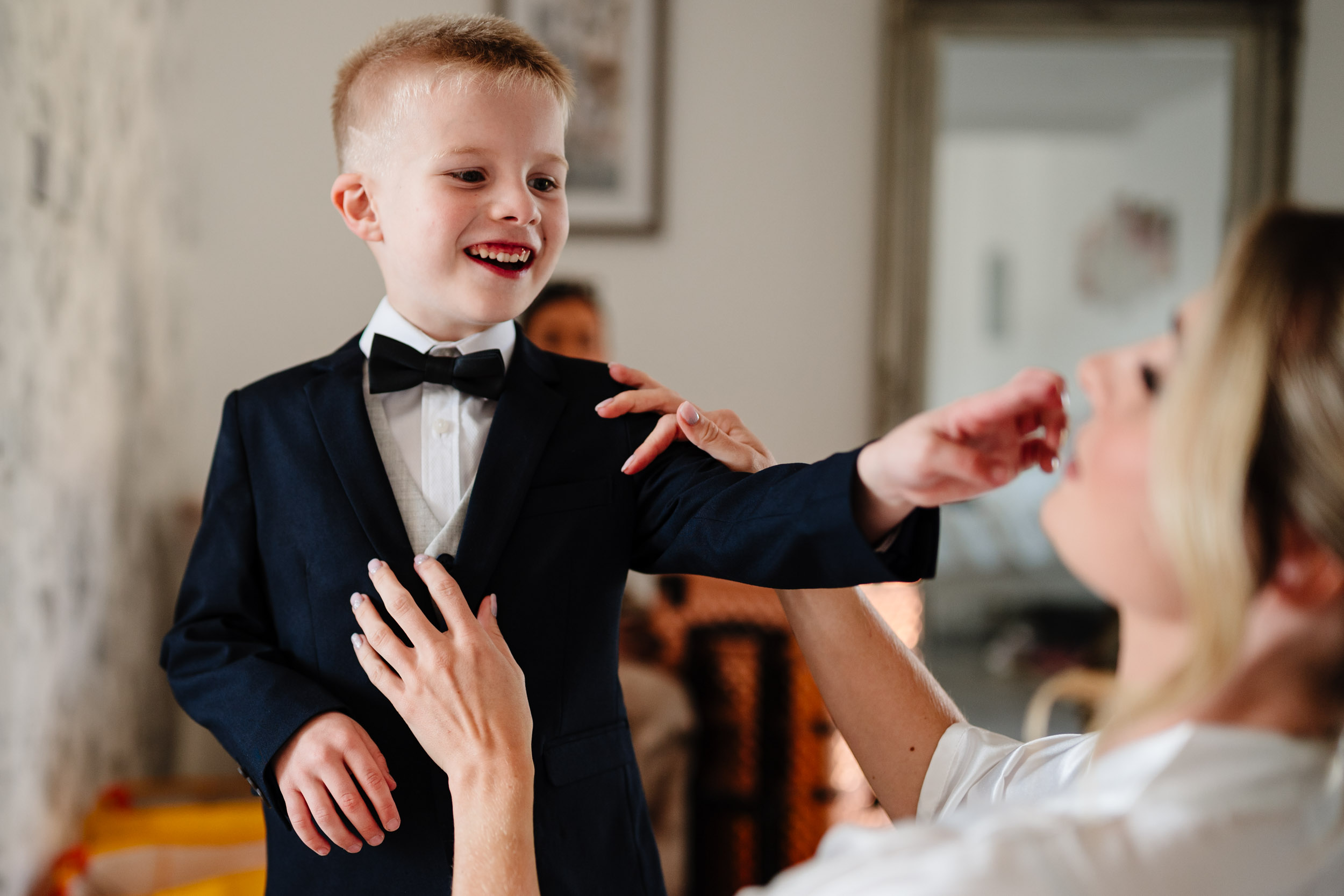 child misbehaving while bride is dressing him up