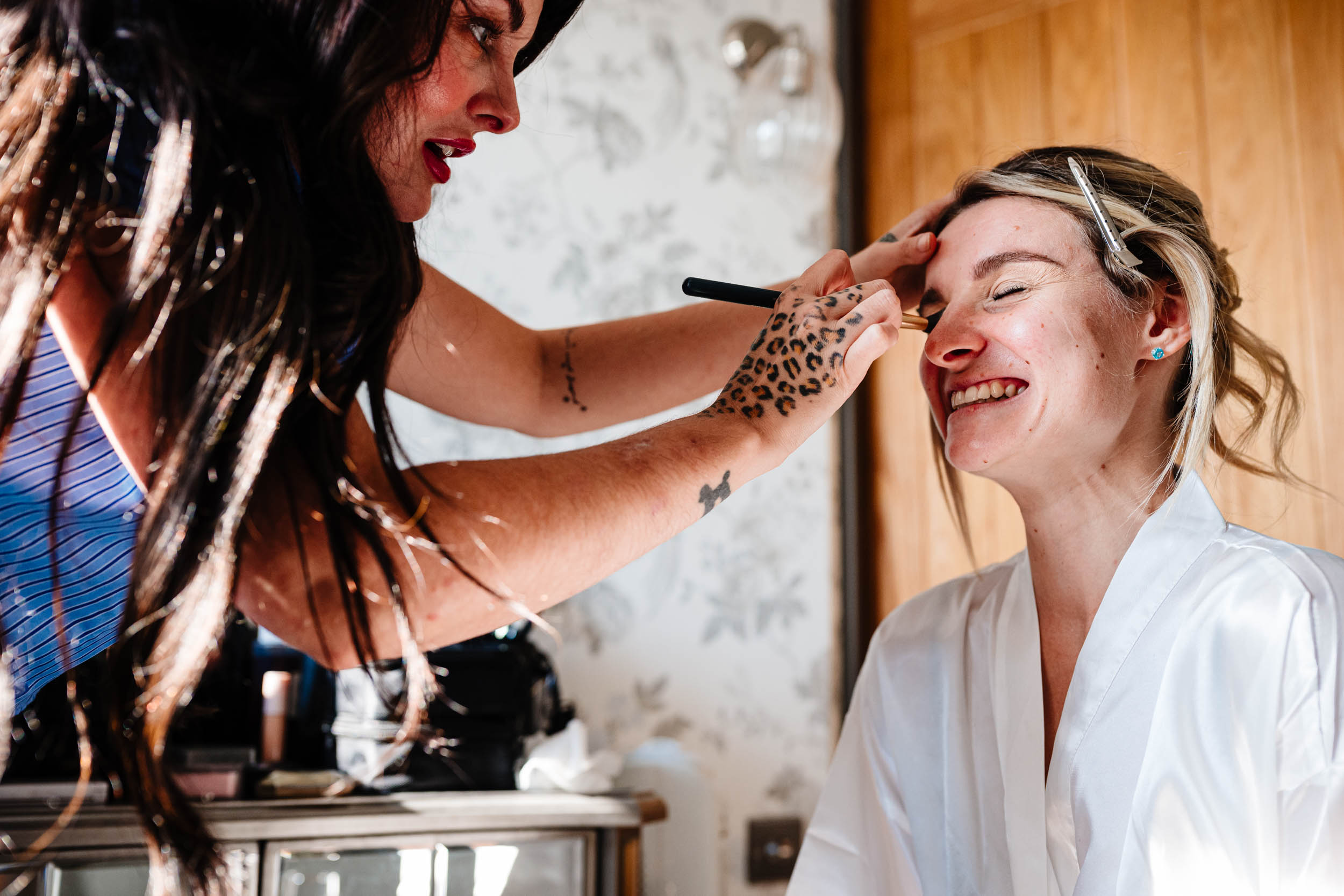 bride laughing while having her make up done
