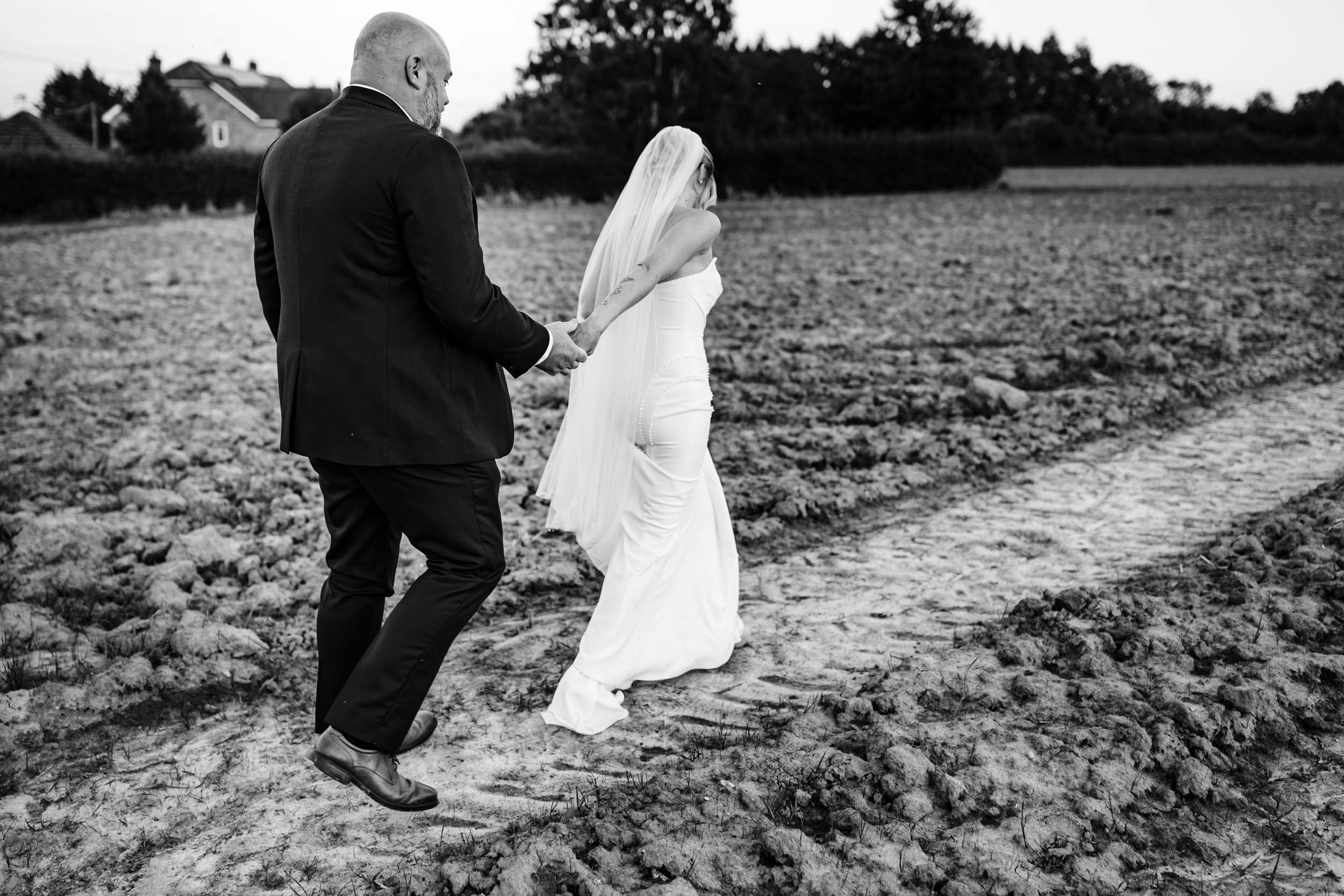 bride and groom walking in a field
