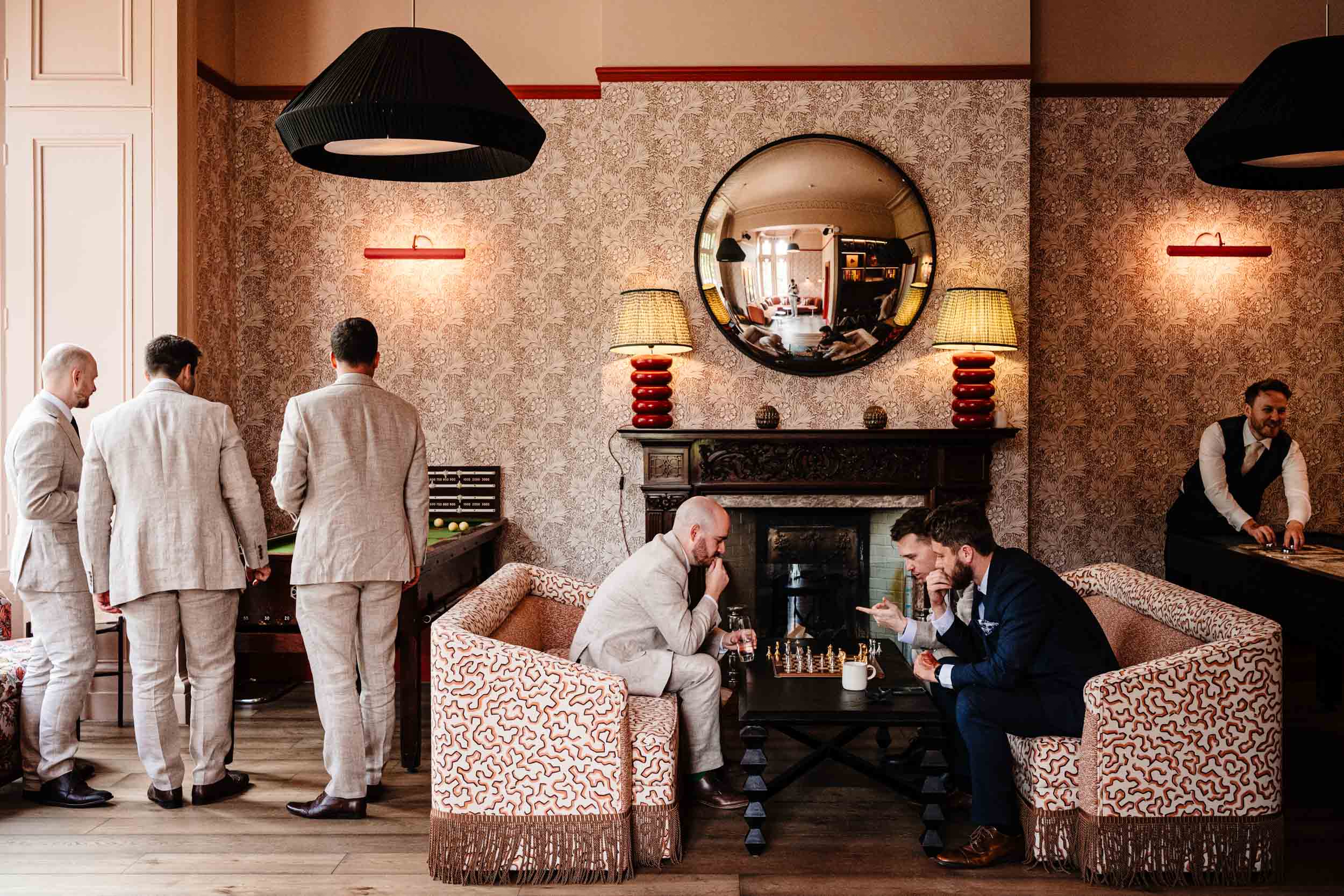 Groomsmen playing chess and pool inside the games room at Hampton Manor