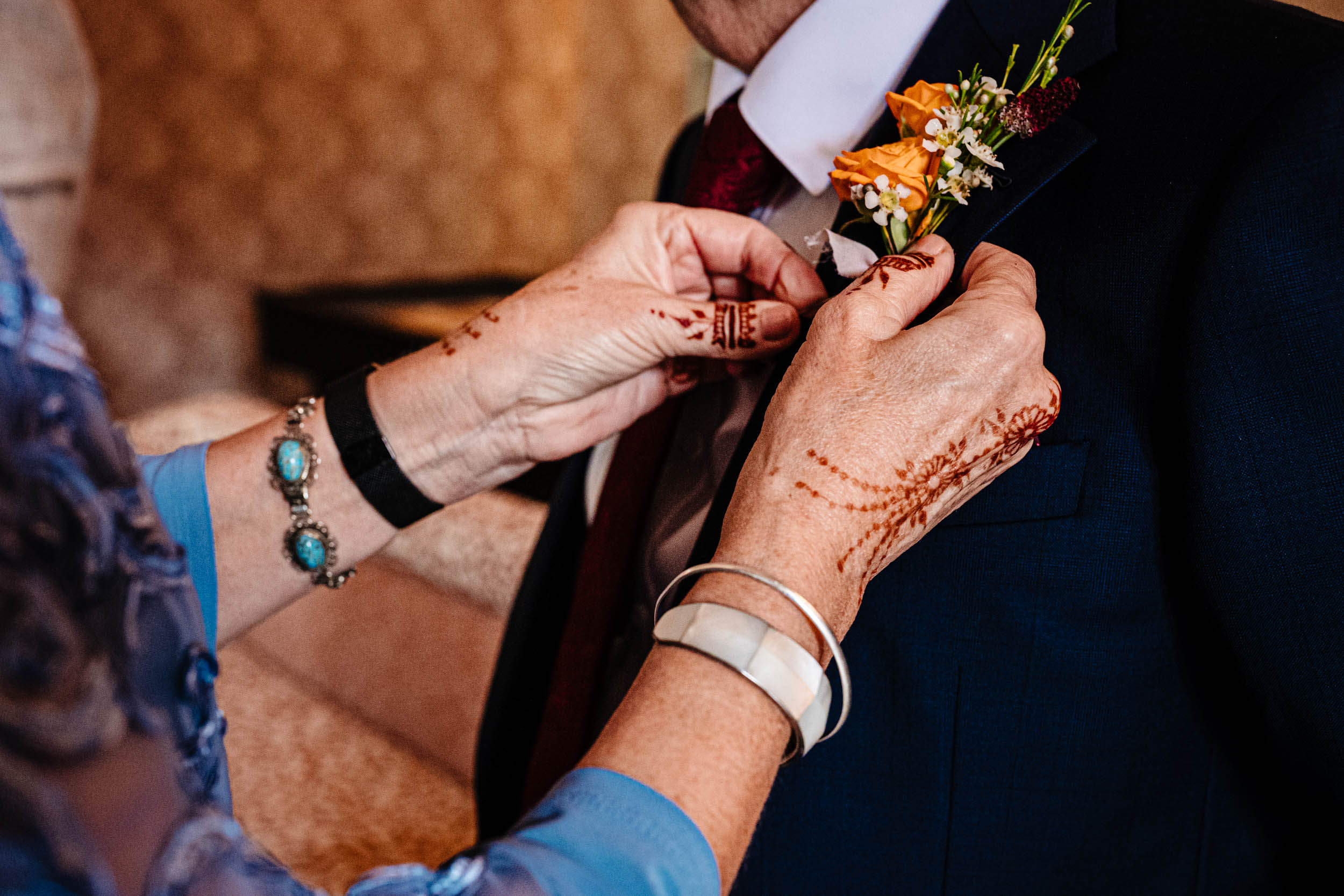 Sam’s mum pinning a boutonniere on Sam’s dad’s suit jacket