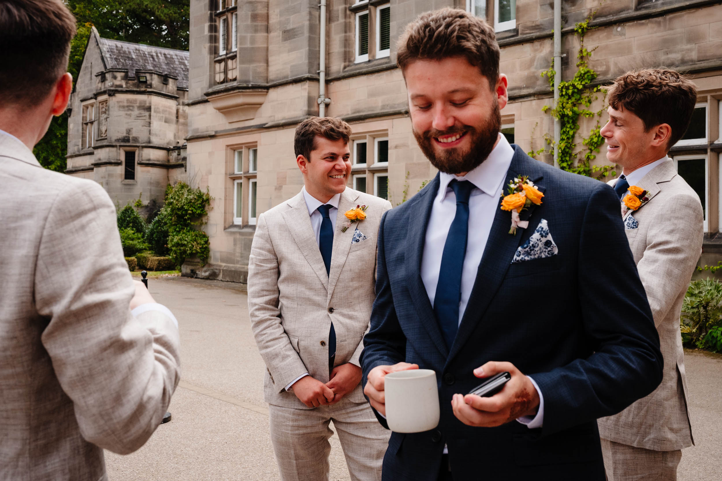 Groomsmen and best man laughing together outside the hotel entrance