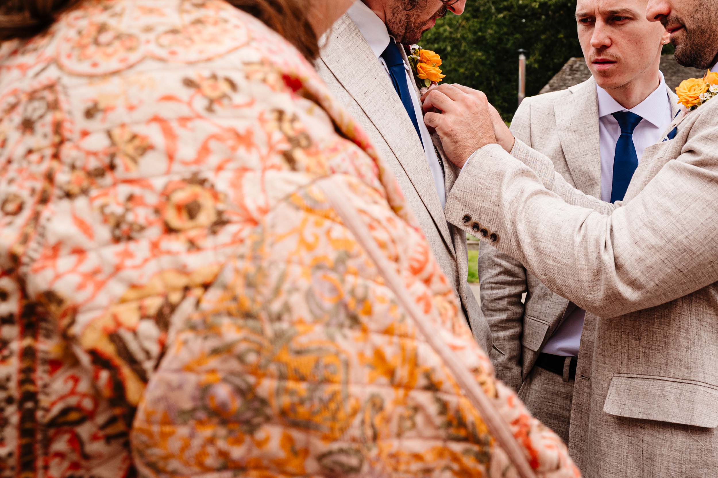 Groomsmen adjusting their buttonholes before the ceremony