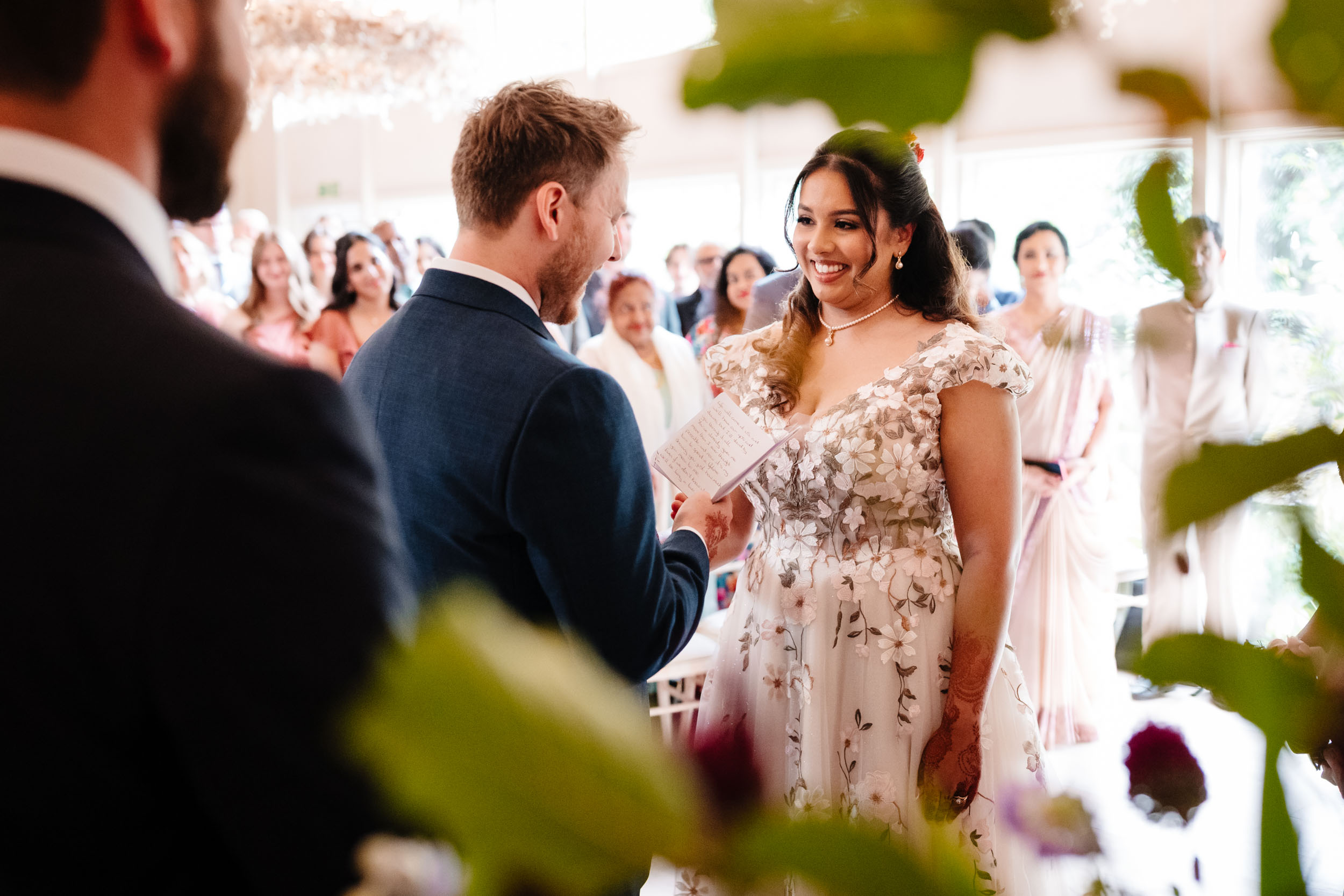 Anika smiling at Sam while he reads his vows