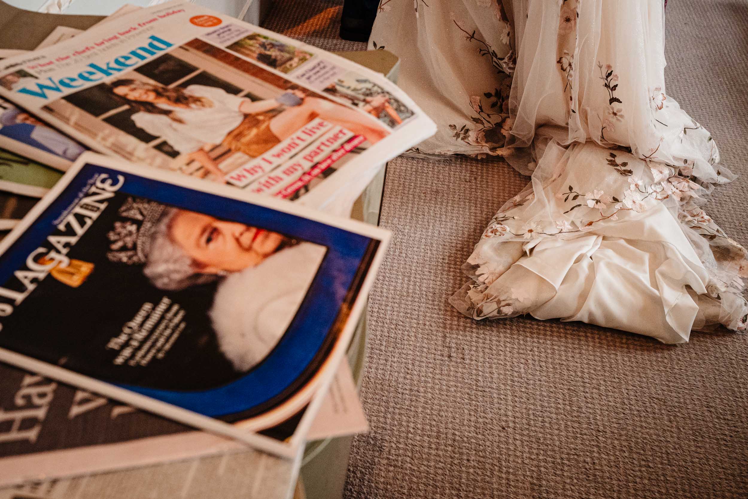 Detail shot of Anika’s dress hanging beside wedding magazines