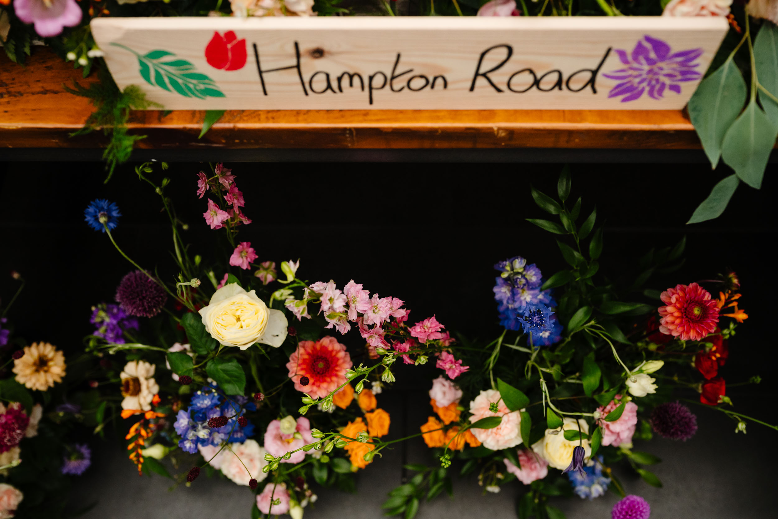 Sign on the top table reading Hampton Road with flowers underneath
