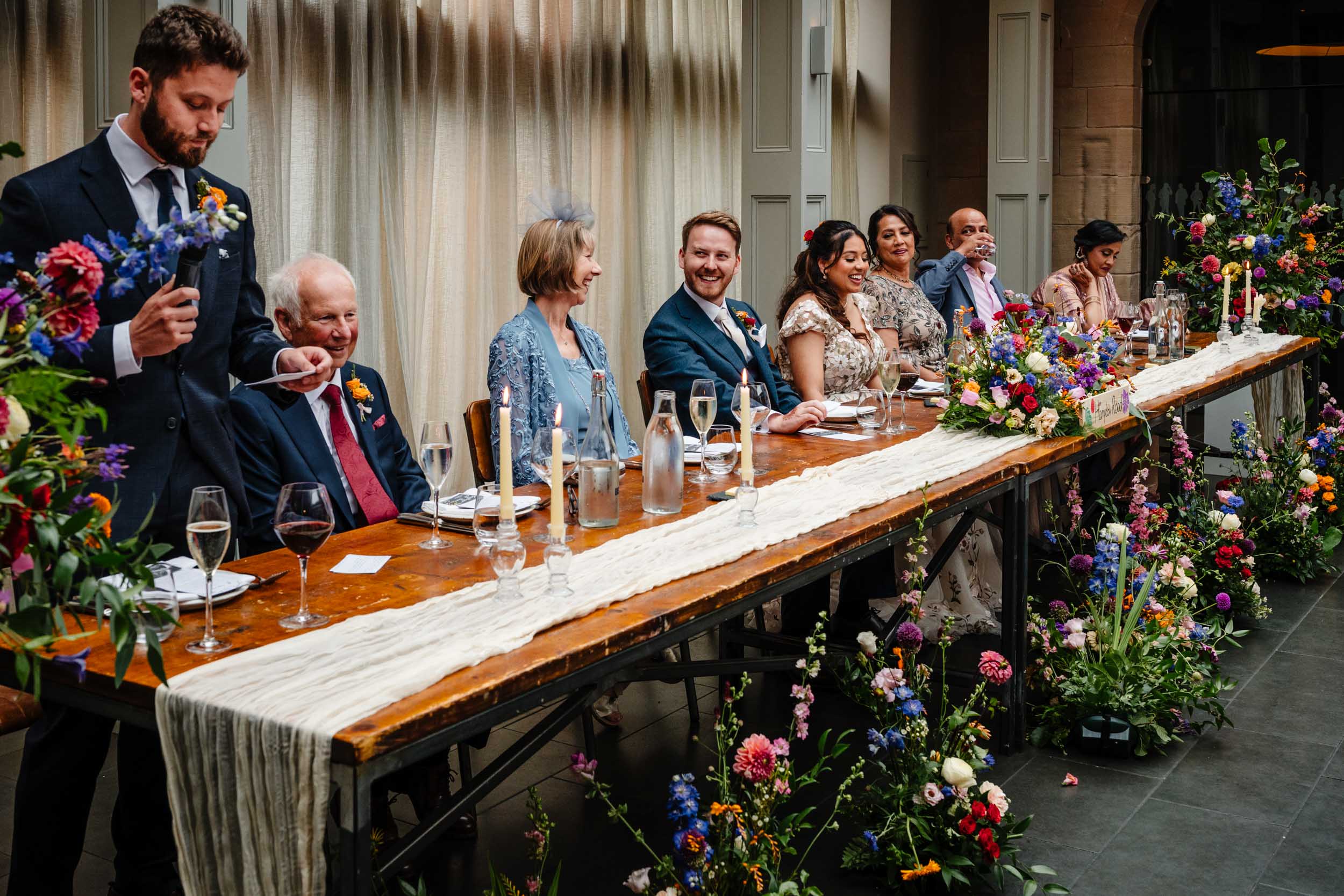 Guests at the top table laughing during the first wedding speech