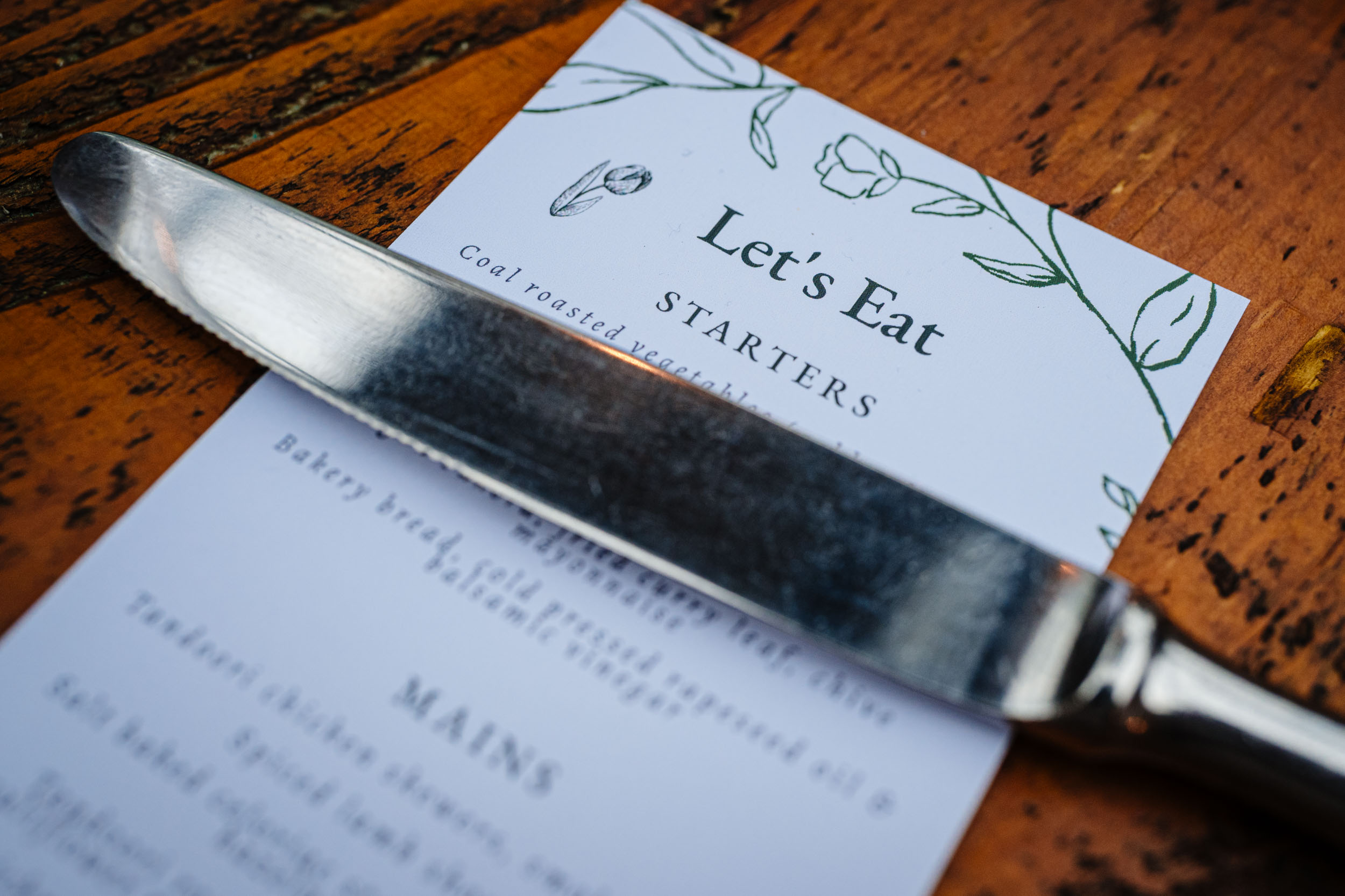 Close up of a knife resting on a plate that says let’s eat