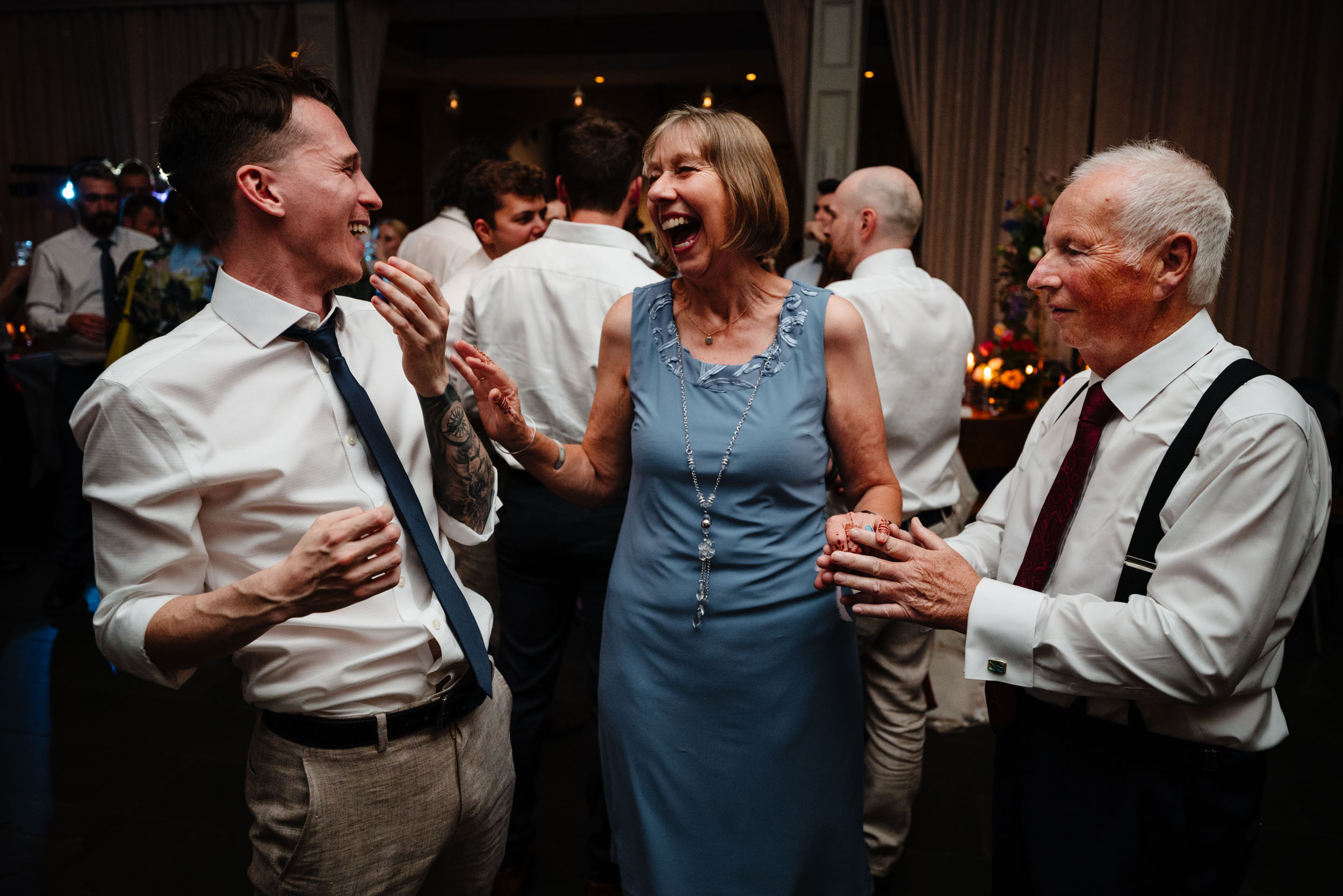 Groom’s mum dad and groomsman laughing together on the dancefloor