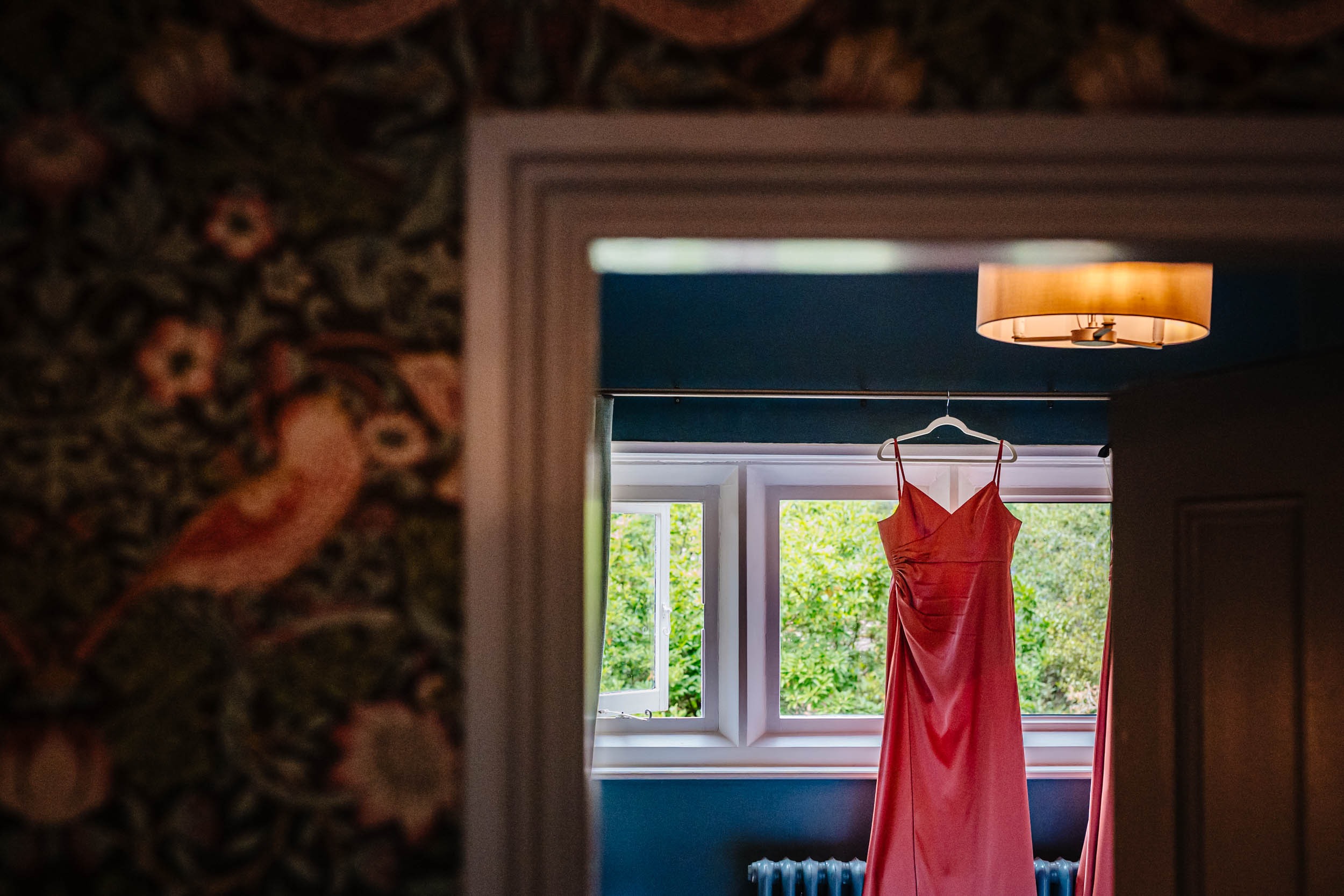 Red bridesmaid dress hanging from a rail in the prep room