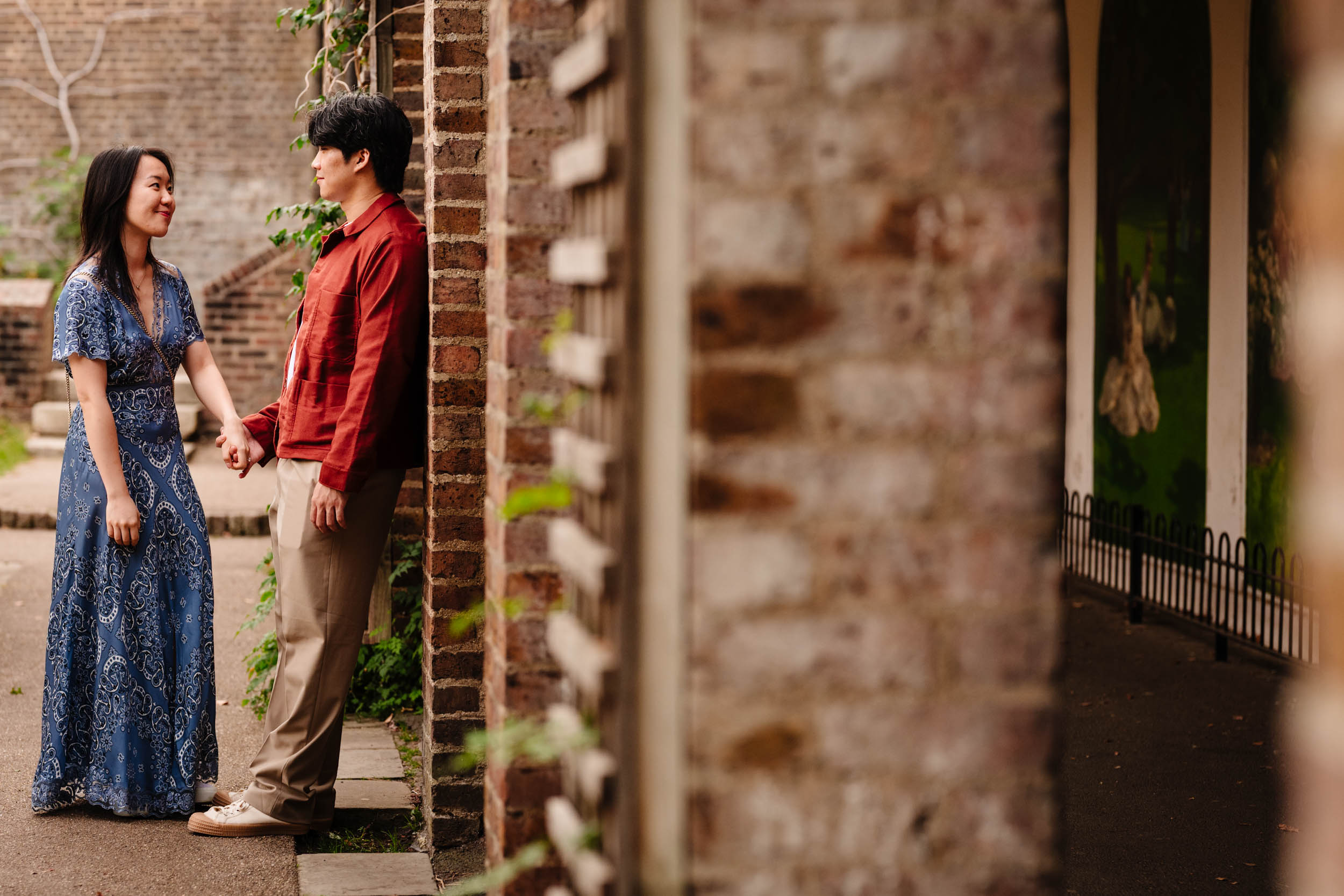 Jonas leaning casually against a wall while chatting with Ariel during their engagement shoot