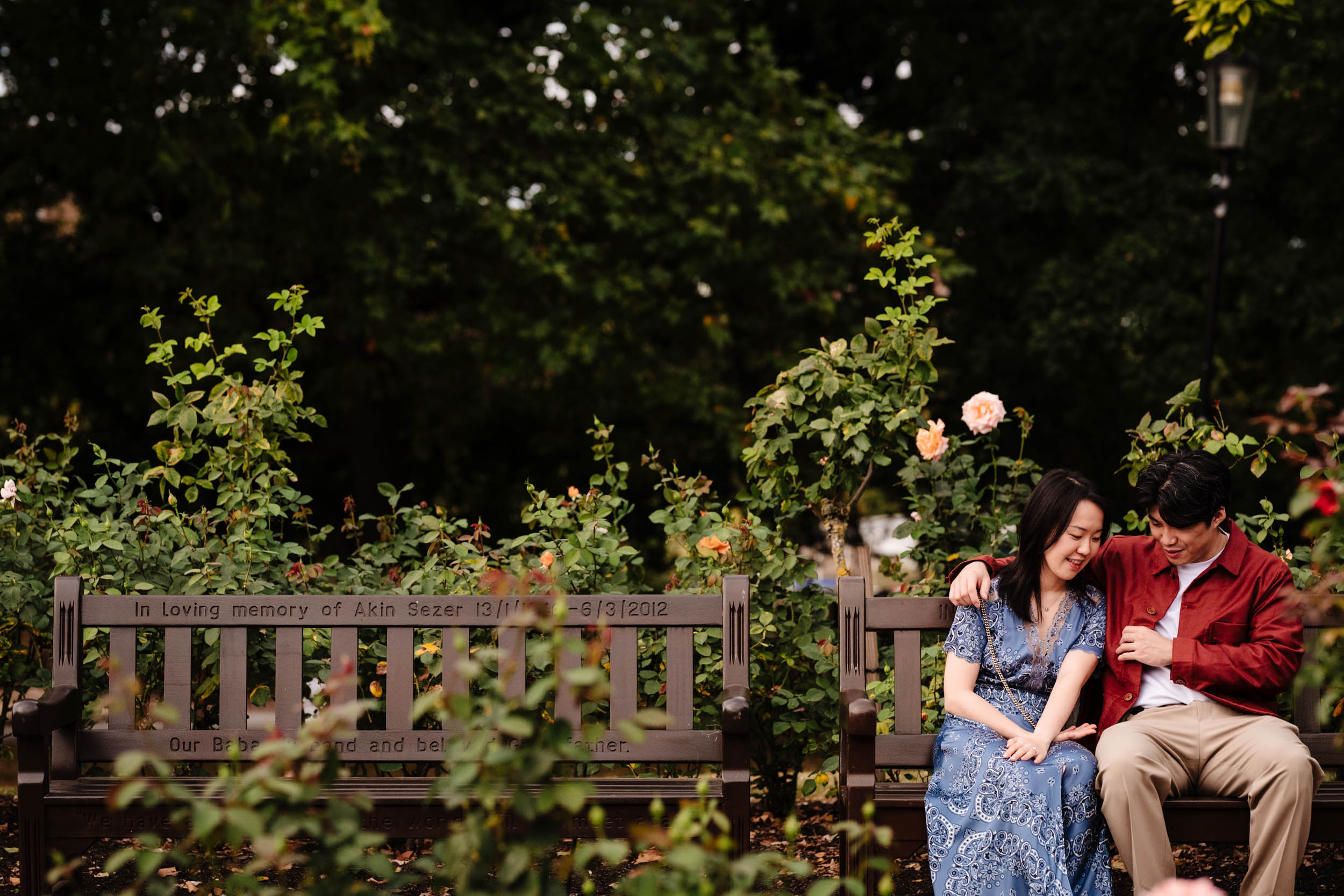 Couple sitting on a bench in Holland Park, laughing and enjoying the moment