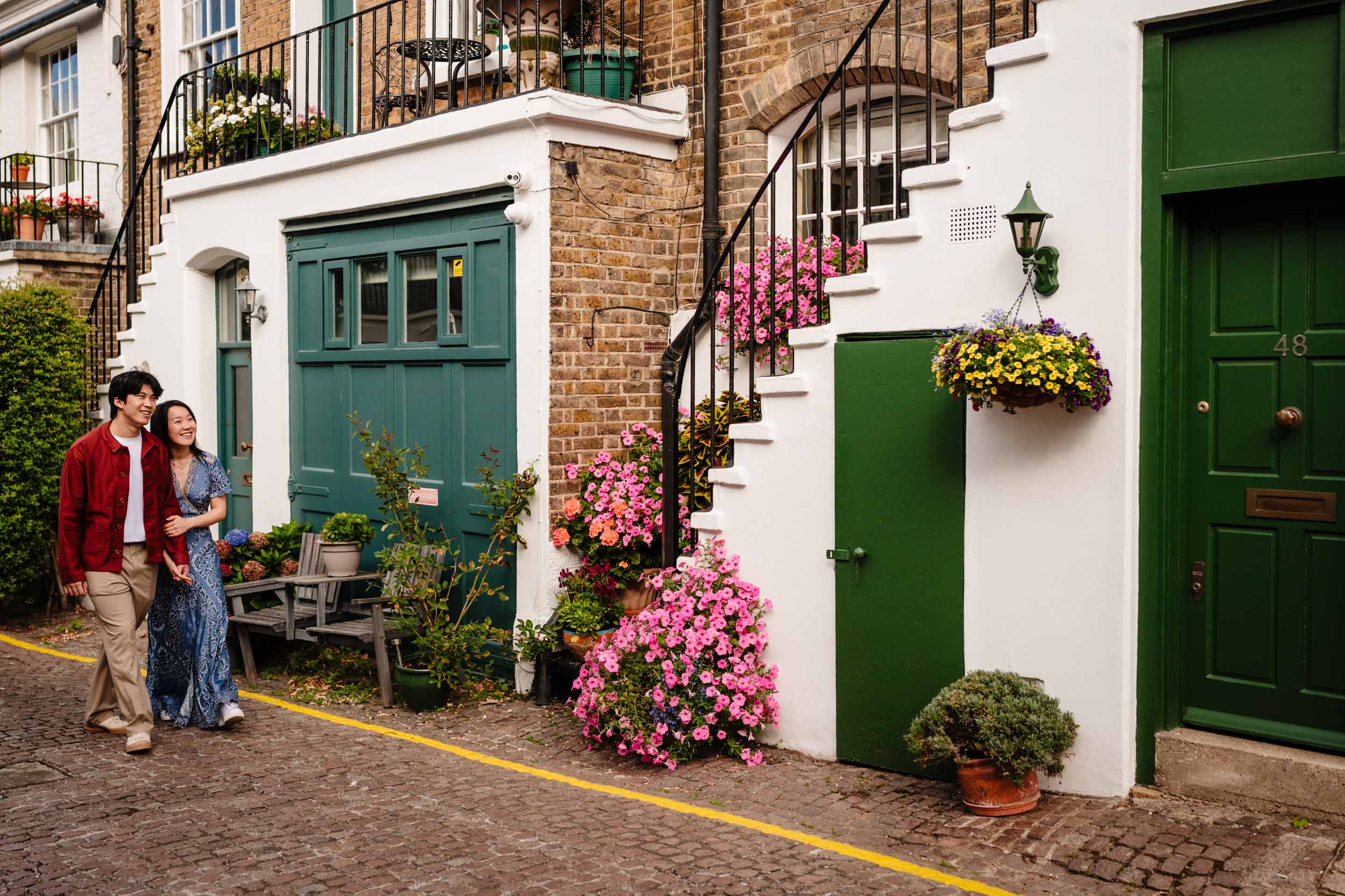 Jonas and Ariel walking along a quiet London street lined with pretty houses