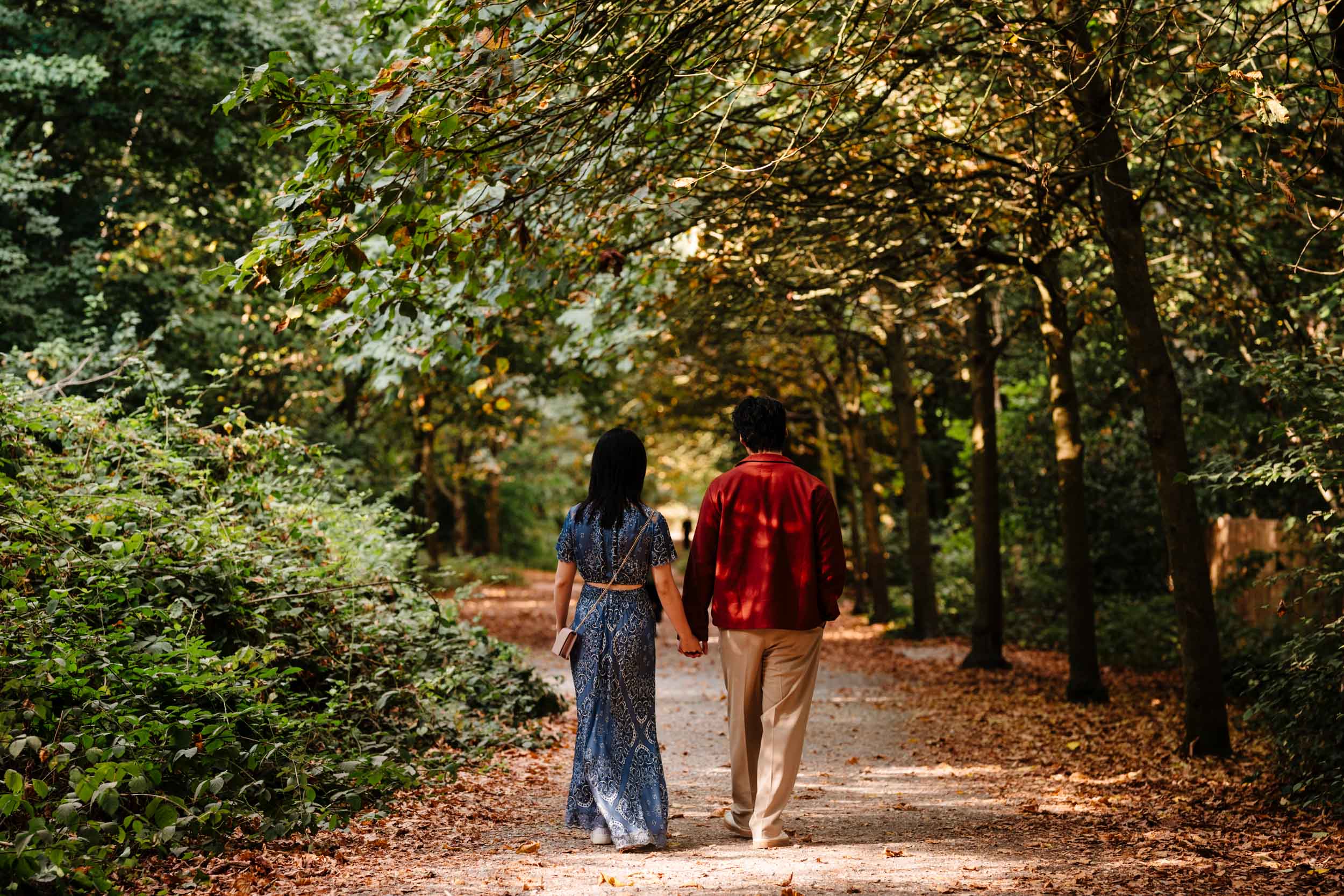 Rear view of Jonas and Ariel walking through the garden paths surrounded by trees