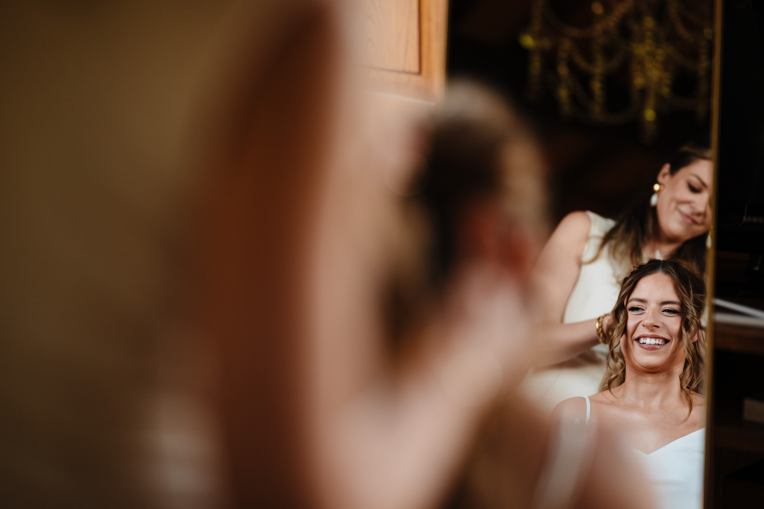 Bride smiling in the mirror during her wedding morning hair styling.
