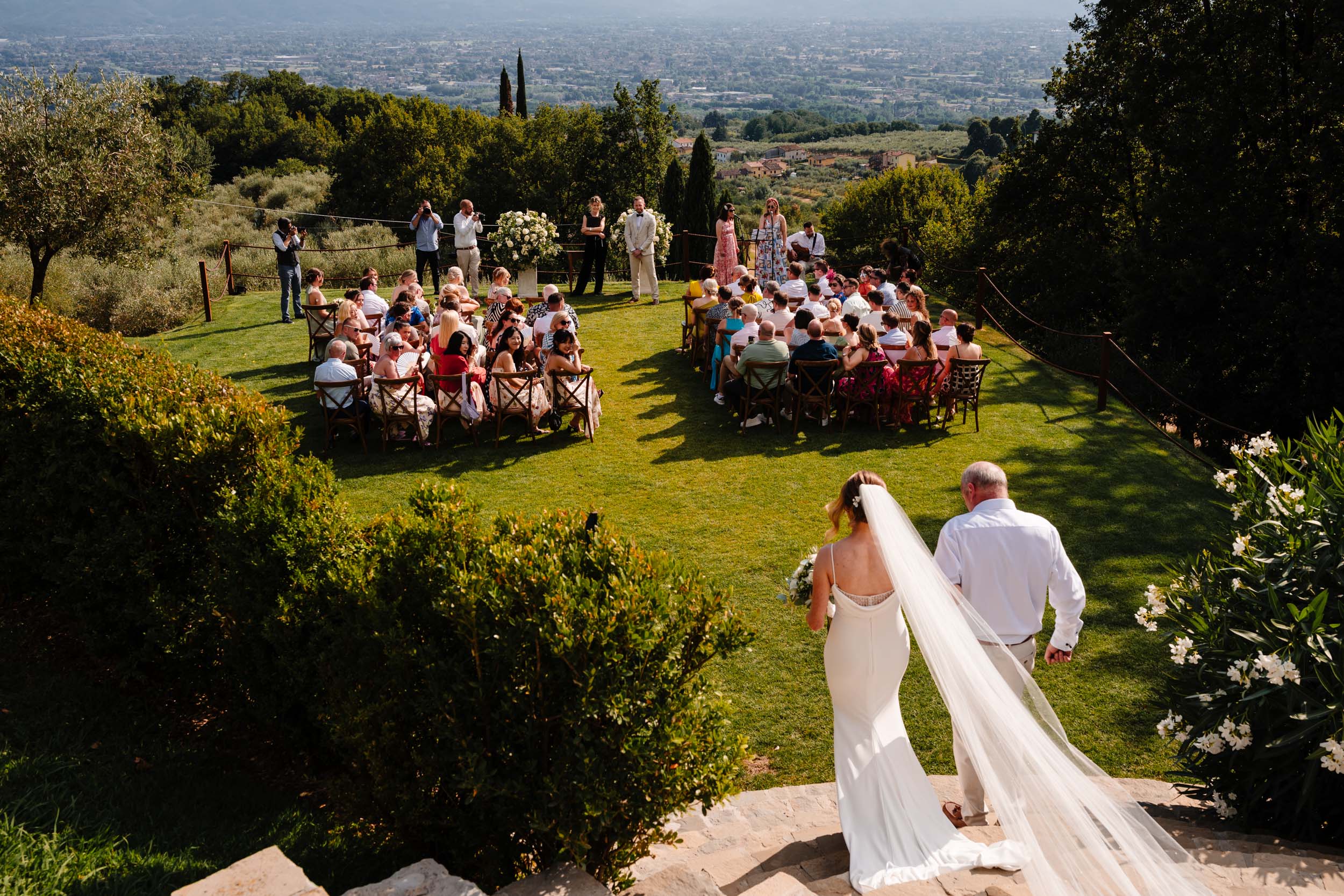 Bride and her dad walking toward the ceremony overlooking the Tuscan hills.