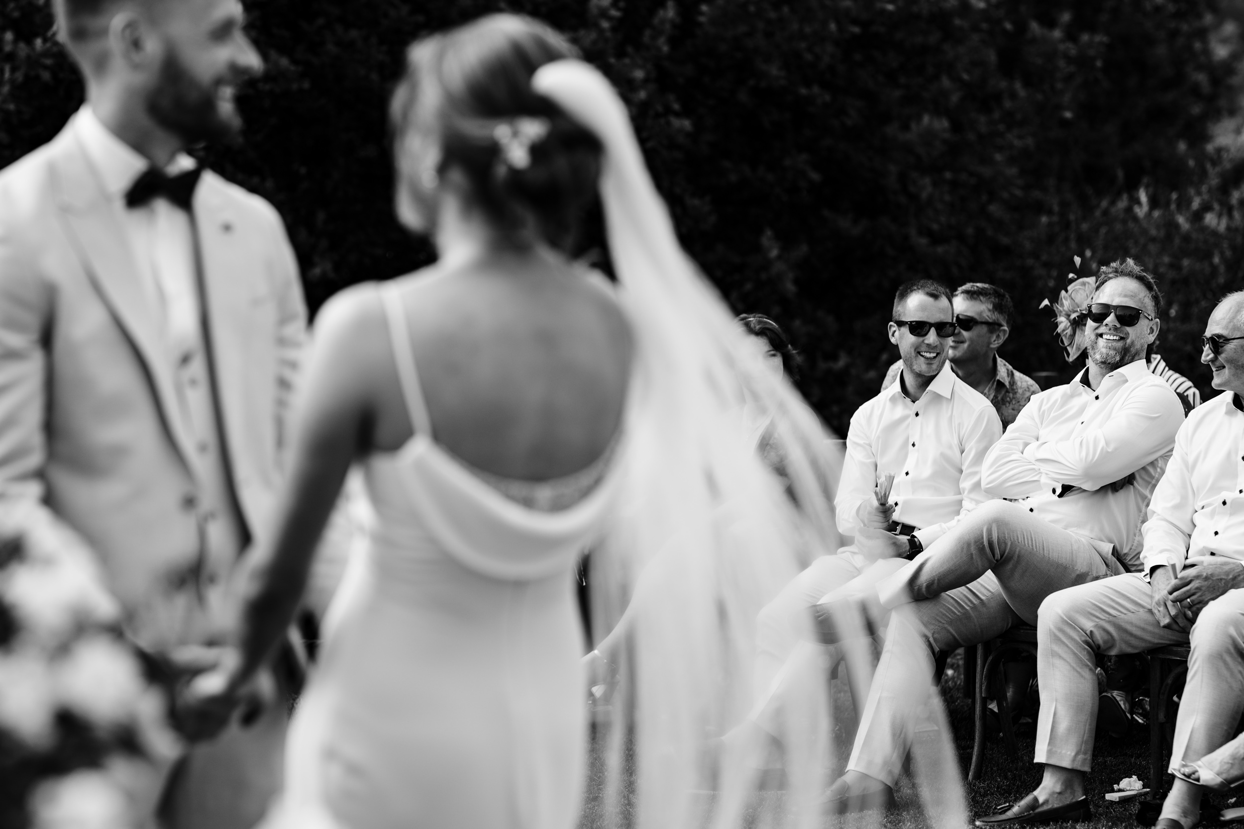 Guests smiling while watching the couple during their outdoor ceremony.