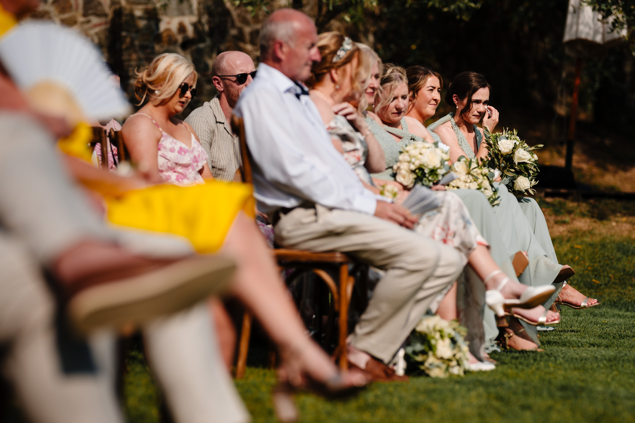 Bridesmaids and guests watching the ceremony, some wiping away tears.