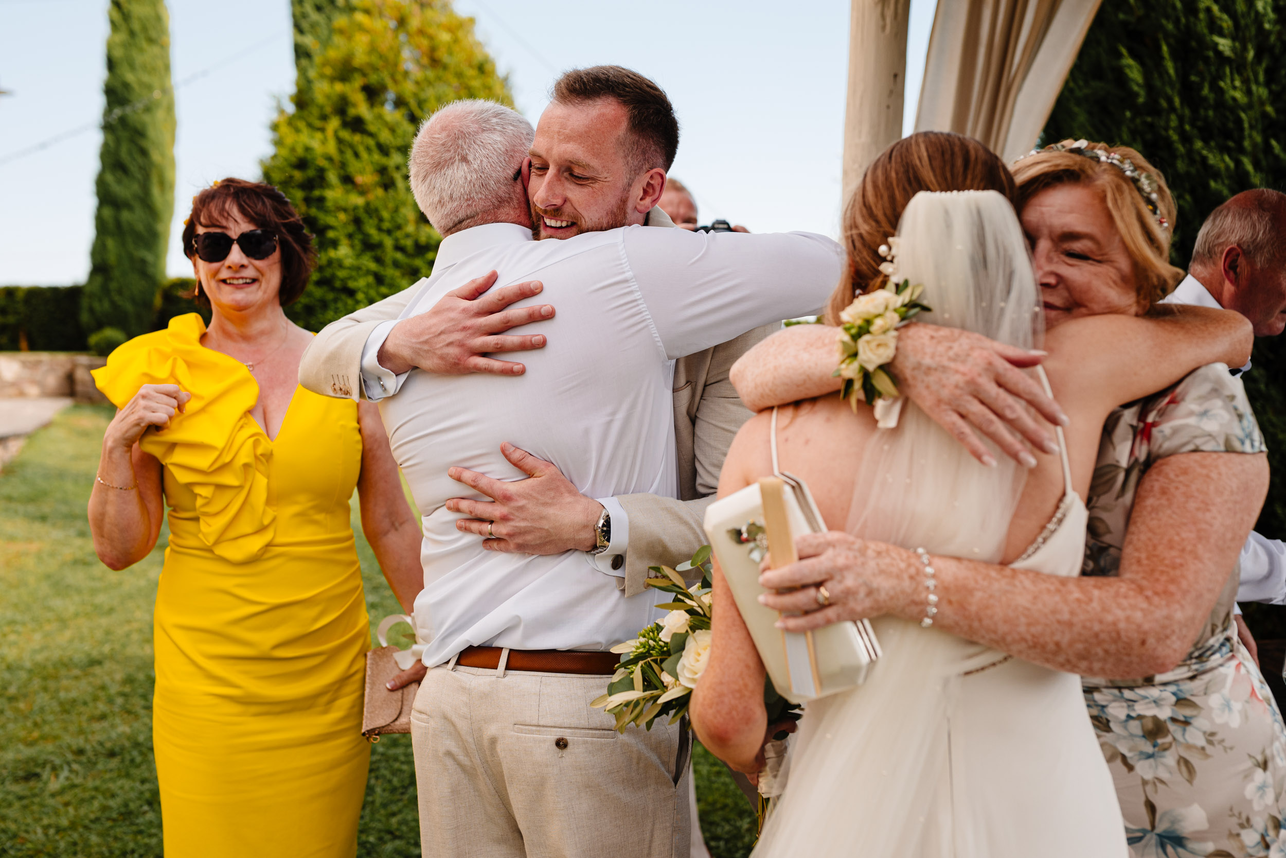Bride and groom embracing family members during the post ceremony greetings.