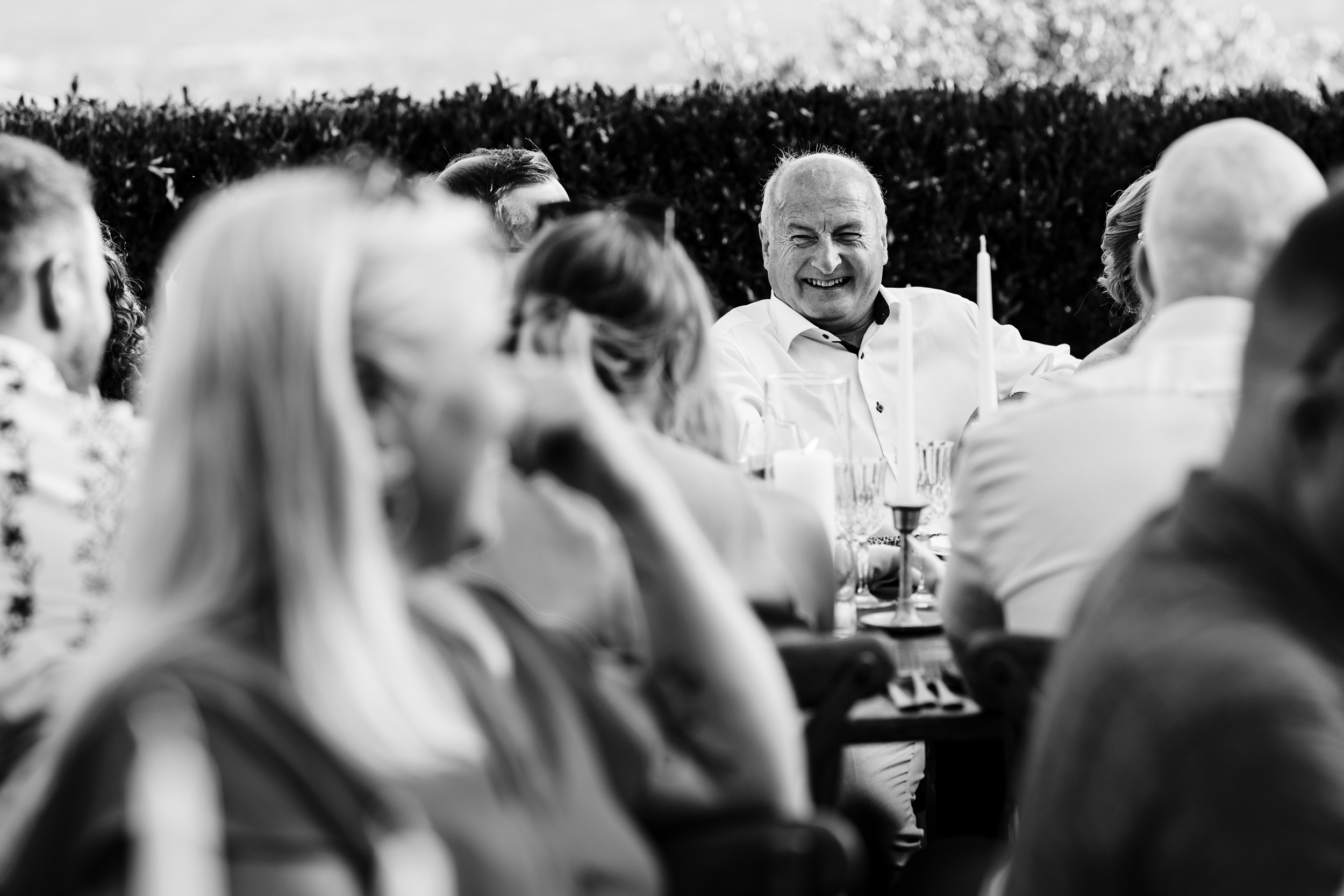 Guest smiling at the dinner table during the outdoor speeches.