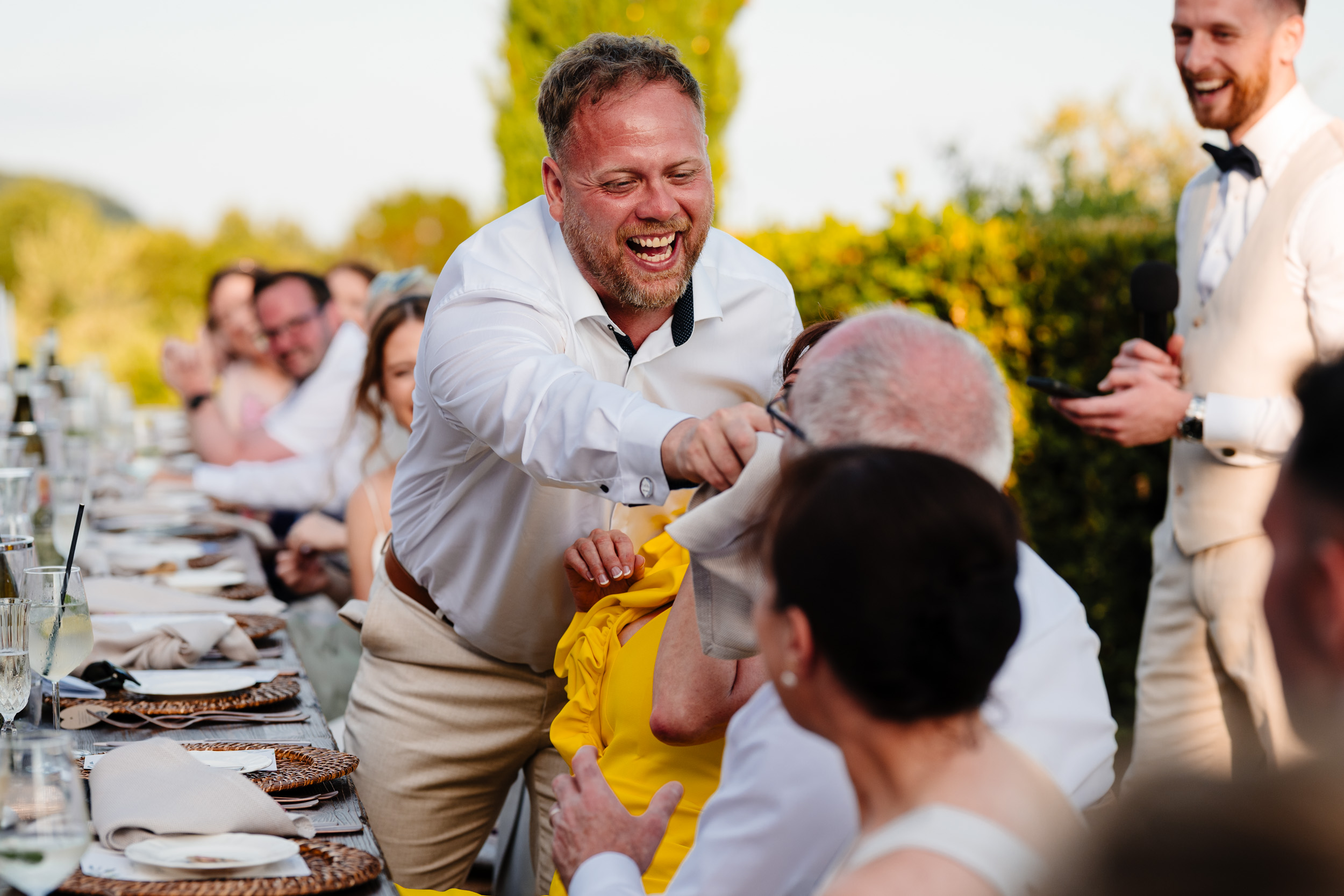 Wedding guest laughing and playfully wiping a napkin on another guest.
