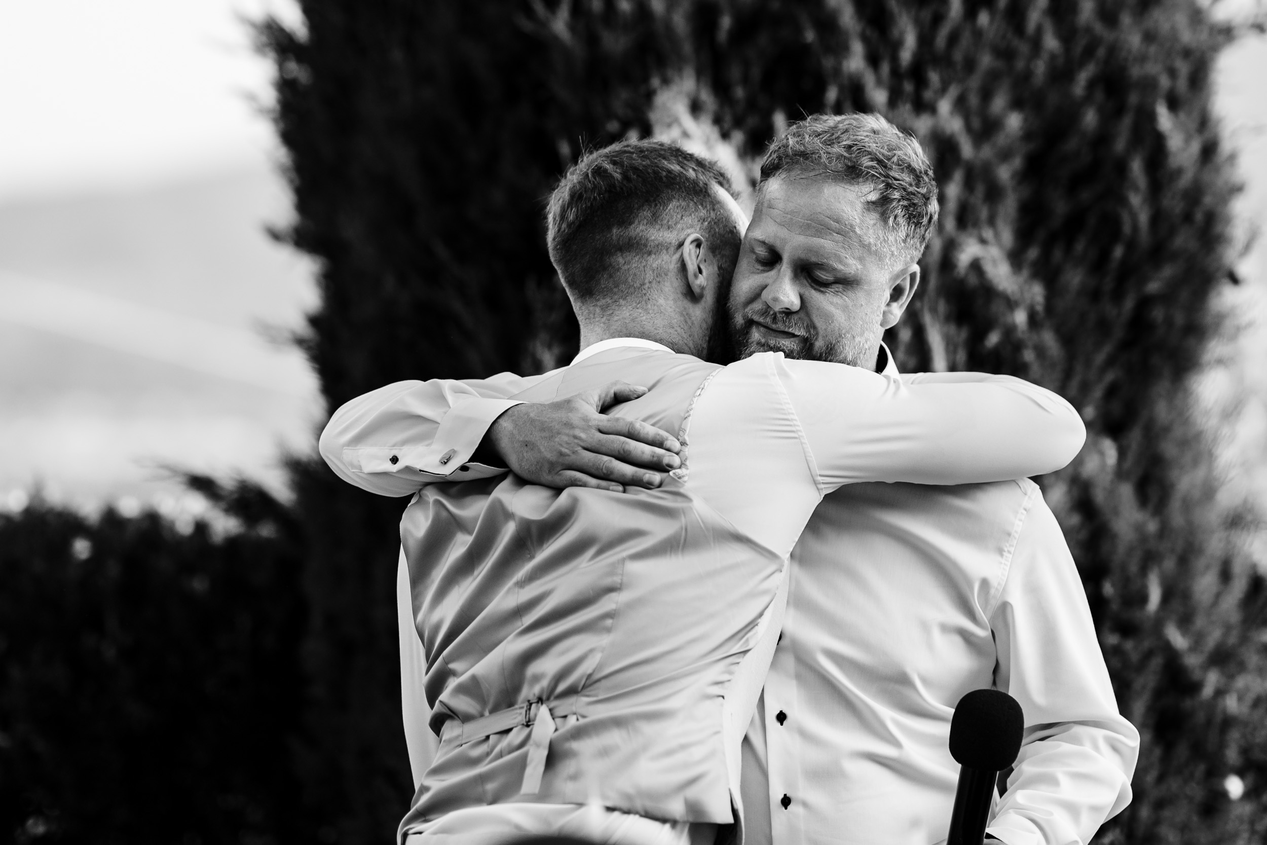 Groom hugging a friend after an emotional wedding speech.