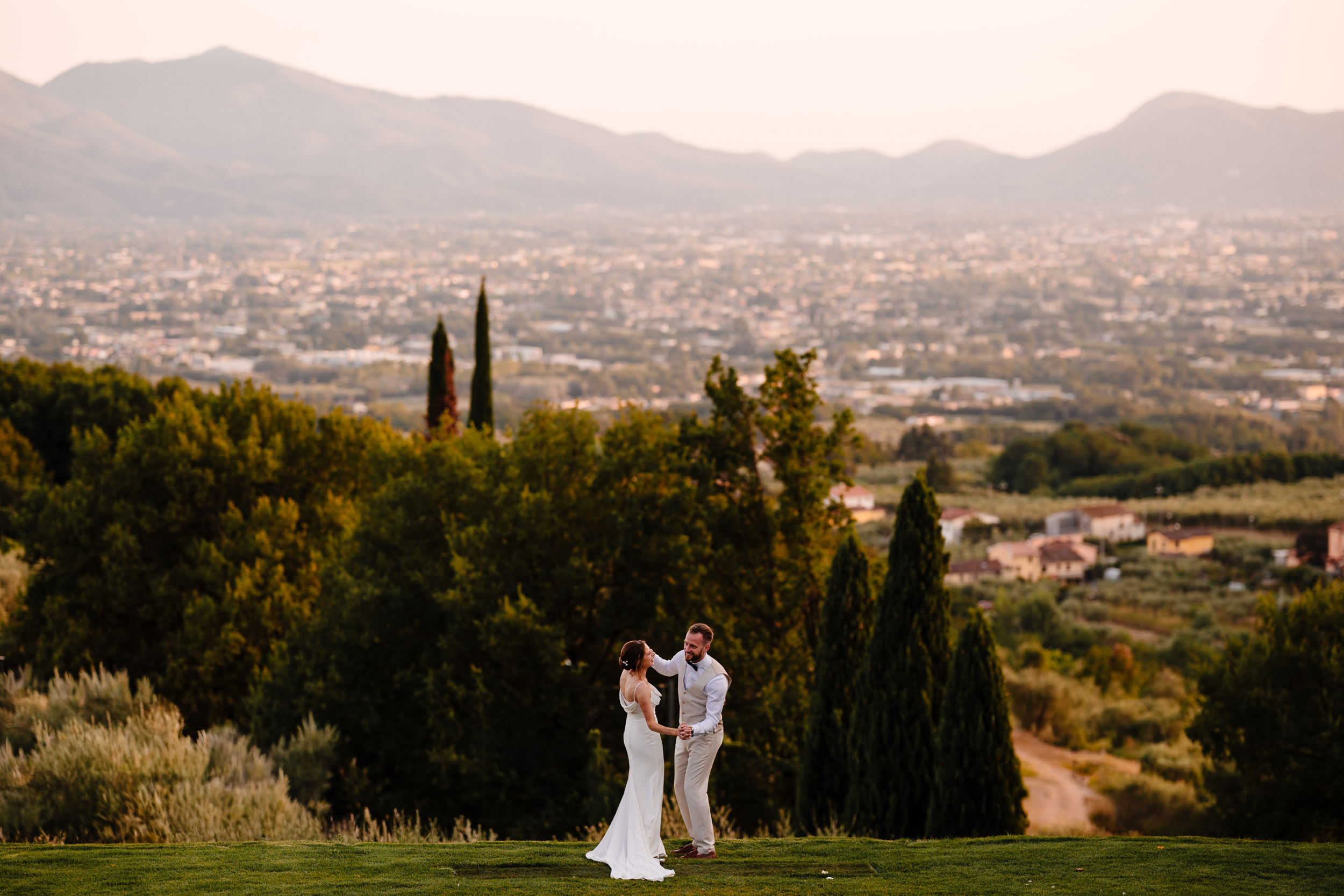 Bride and groom dancing with panoramic views of the Tuscan landscape in the background.