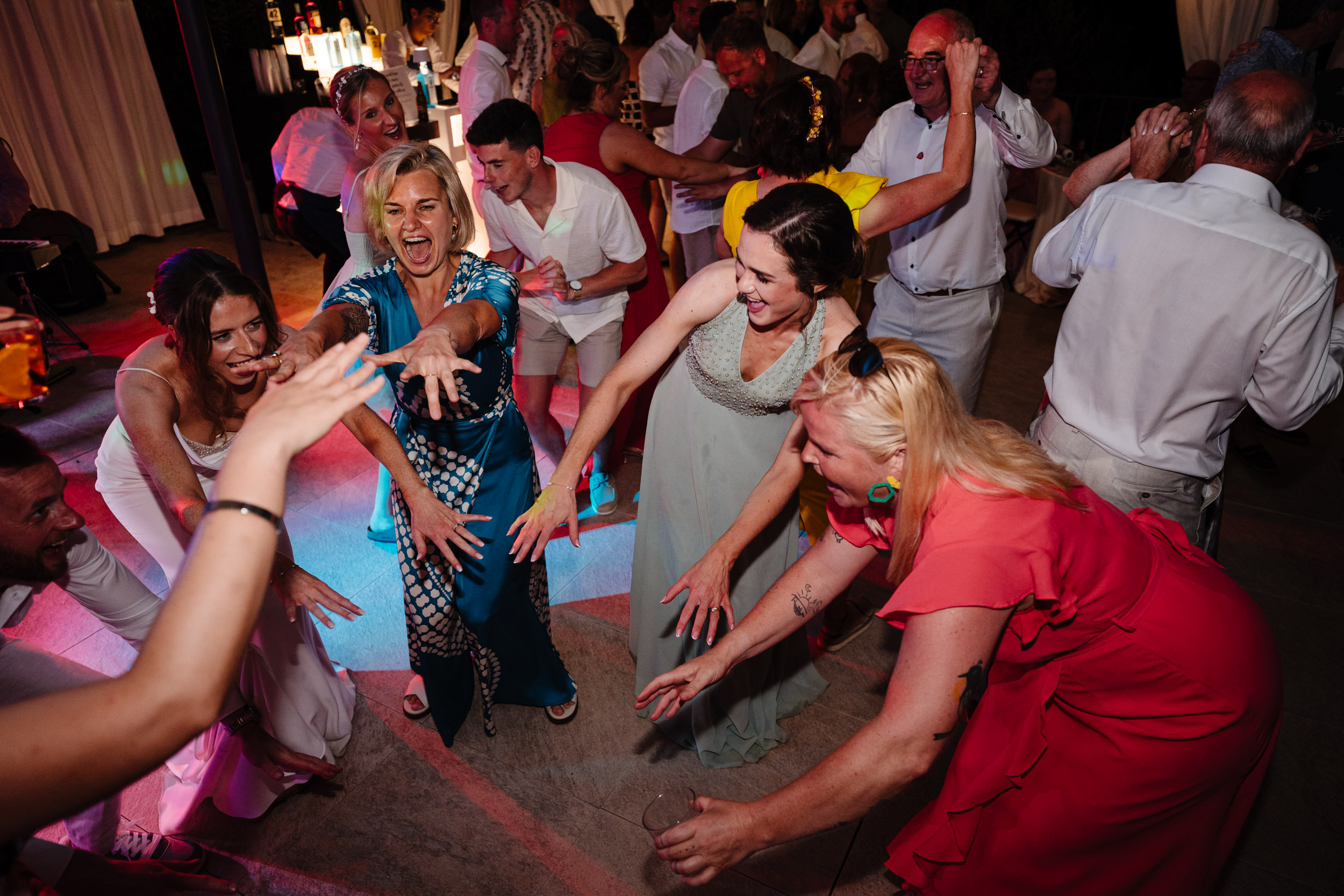 Wedding guests dancing in a circle together during the evening party.