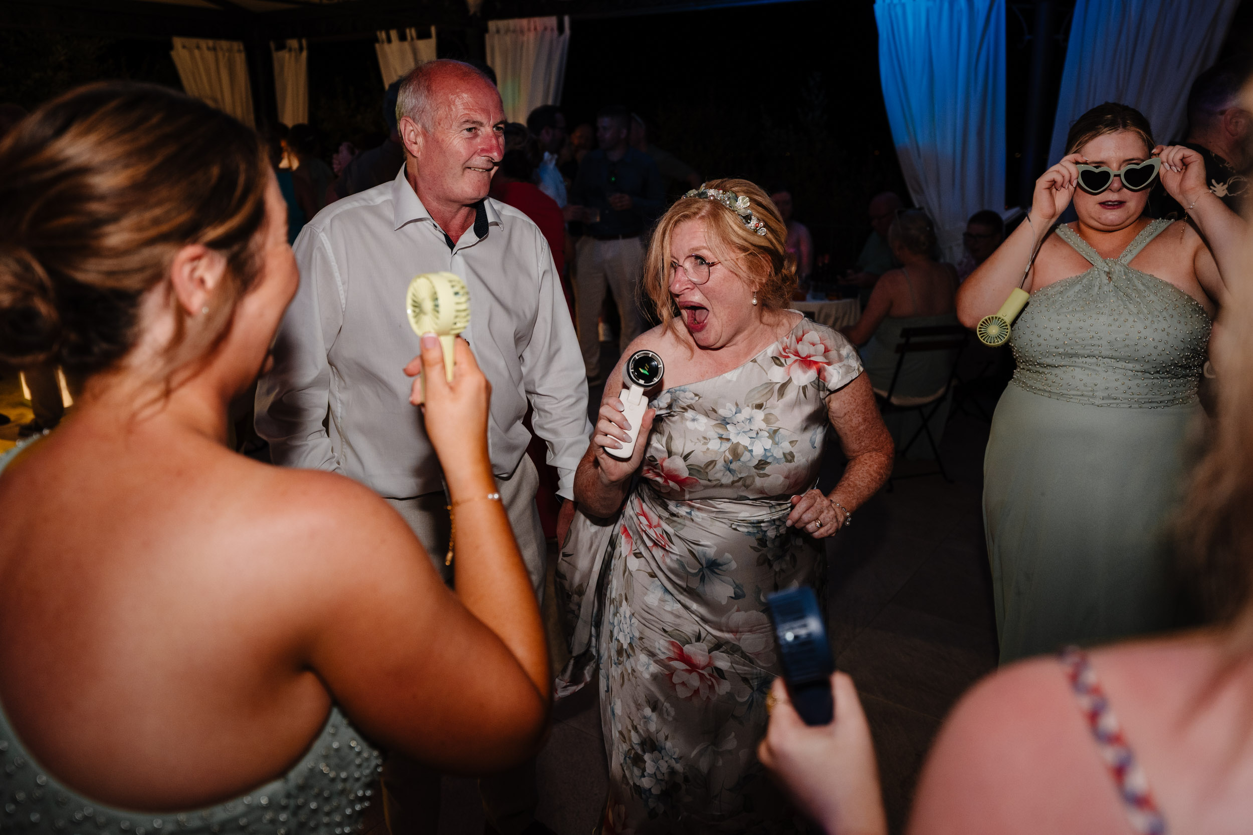 Guests dancing and using small handheld fans to cool down on the dancefloor.