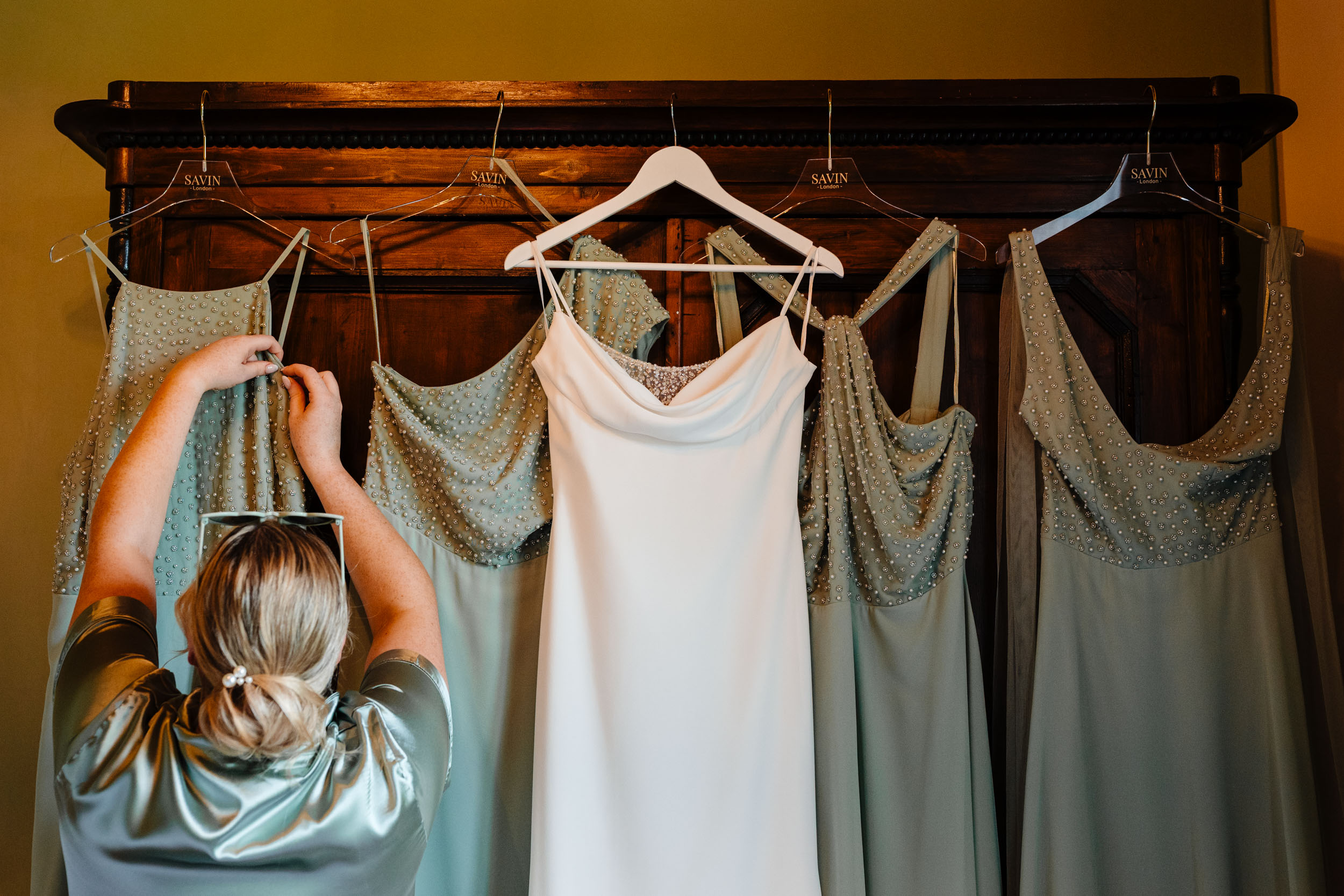 Bridesmaids’ dresses and the bride’s wedding dress hanging inside the villa.