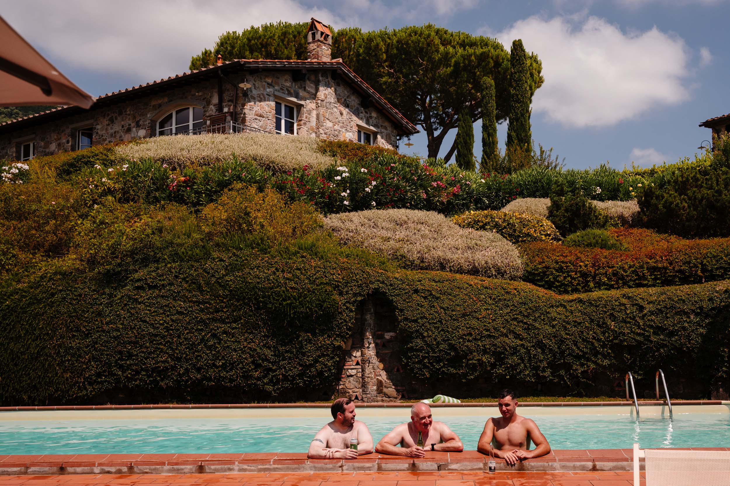 Groomsmen relaxing with drinks in the pool at Casale de Pasquinelli.