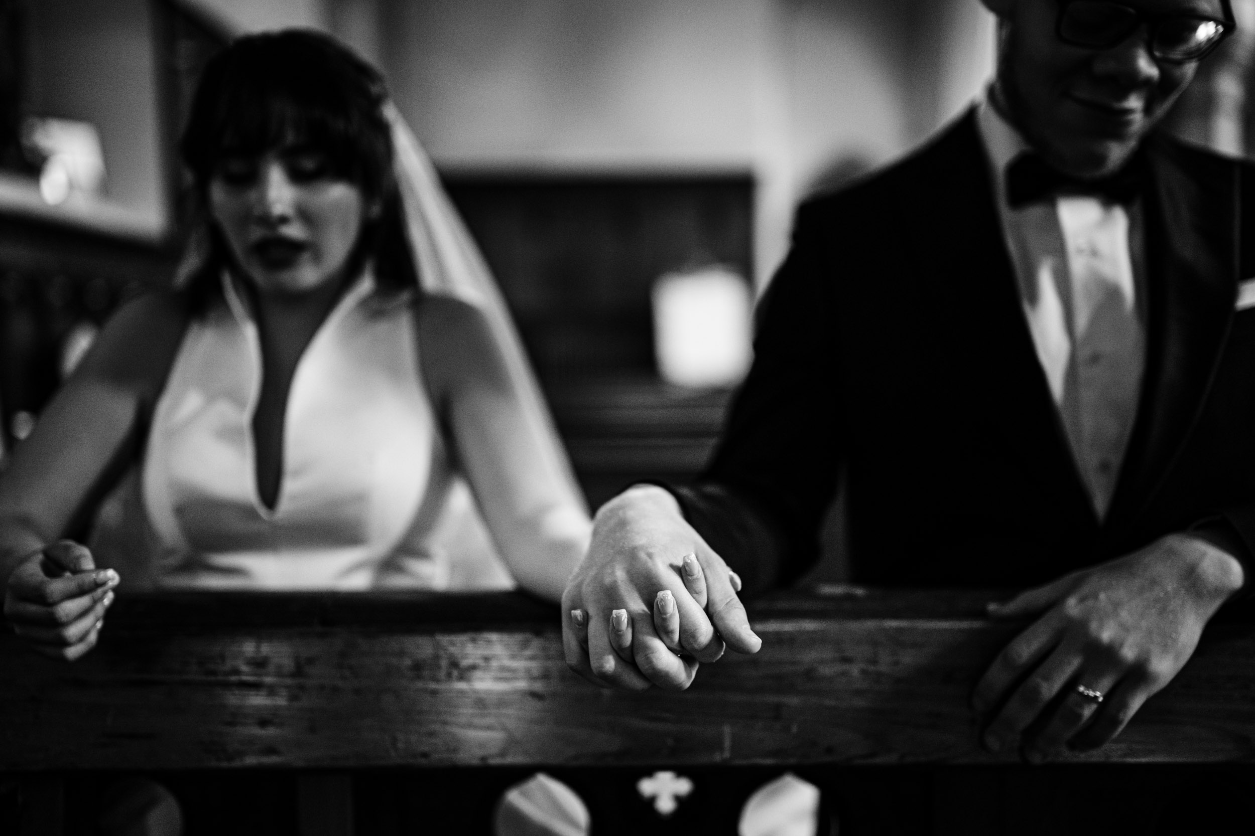 Close-up of Sylvia and Joe holding hands while praying in the church.
