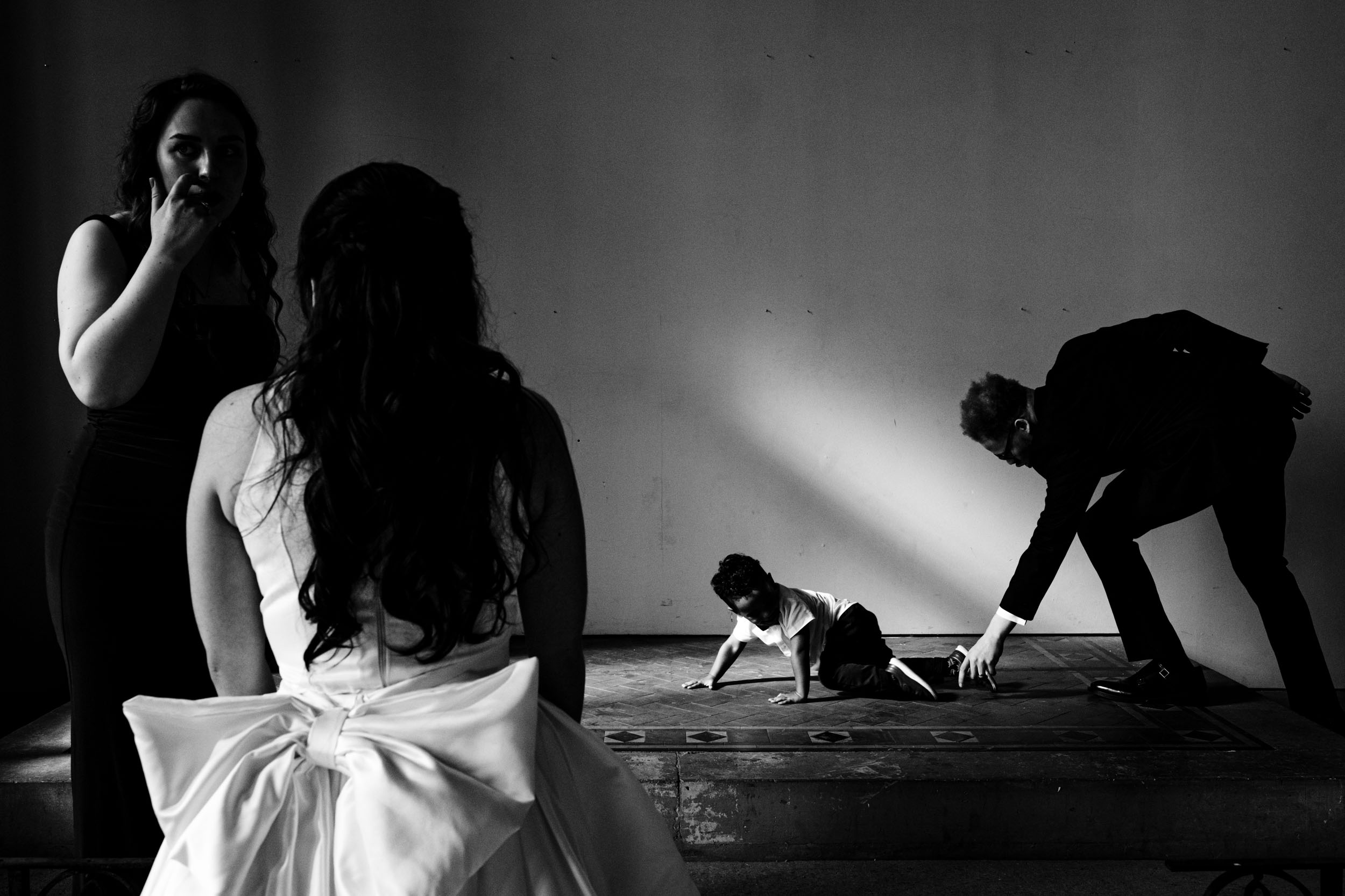 Black and white photo of Joe playing with his nephew while Sylvia talks to the child’s mum, relaxed family moment.