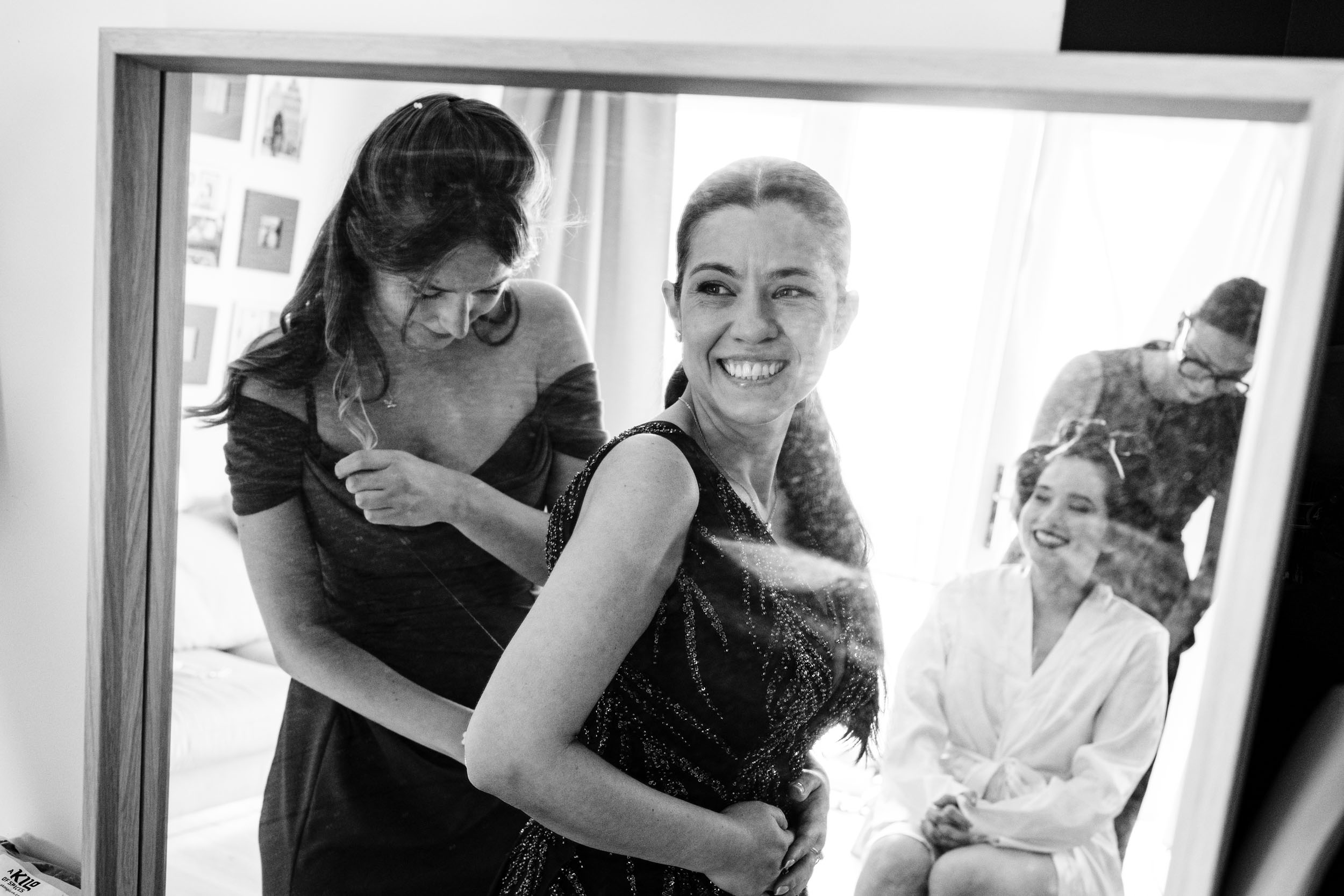 Mirror reflection showing Sylvia, her maid of honour, her mum and the hairdresser sharing a quiet moment.