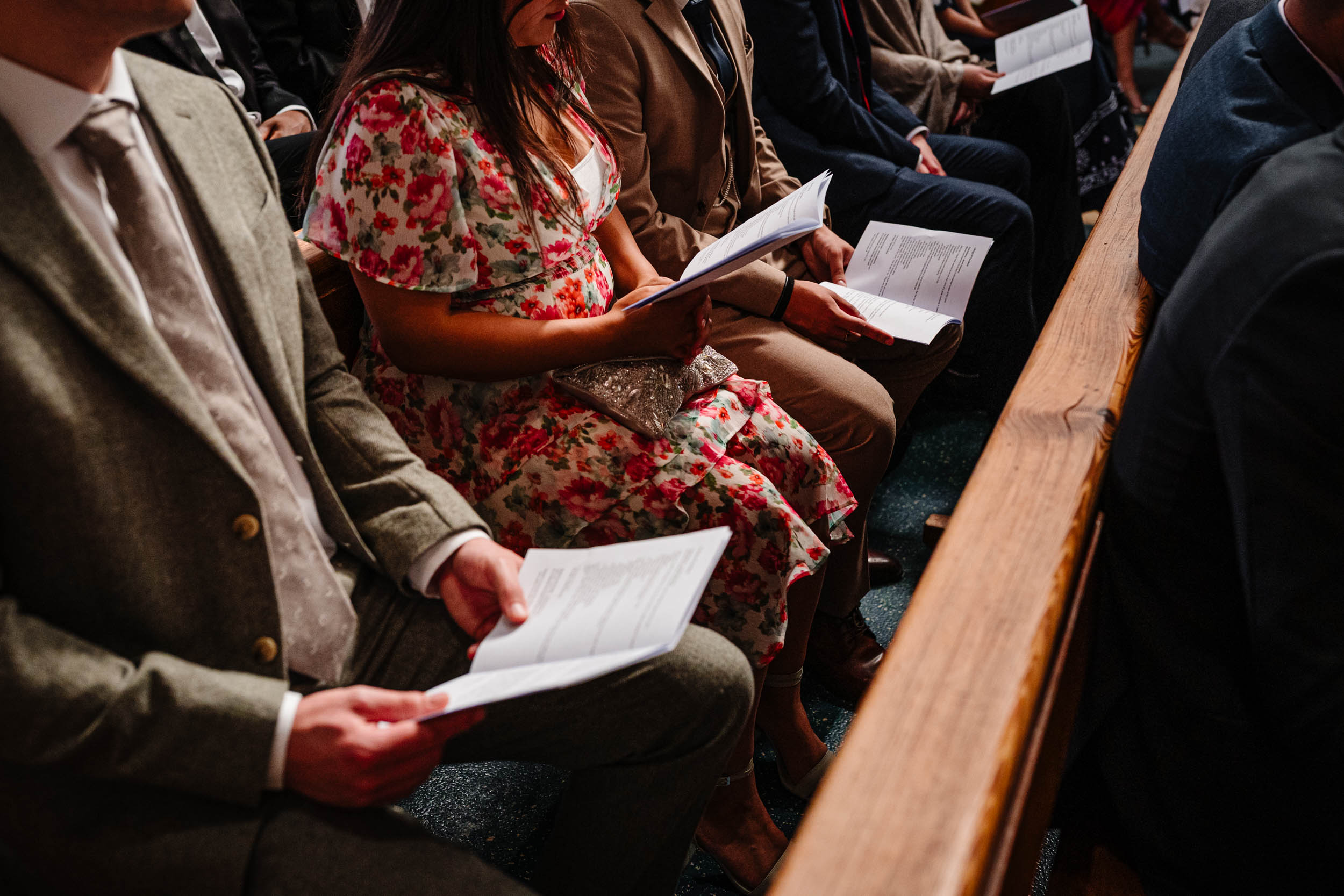 Wedding guests holding the Order of Service booklet during the ceremony.