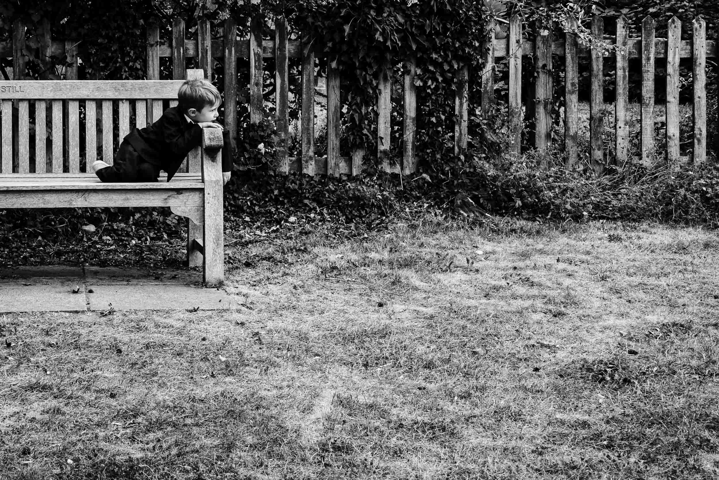 Young boy sitting on a bench looking into the distance