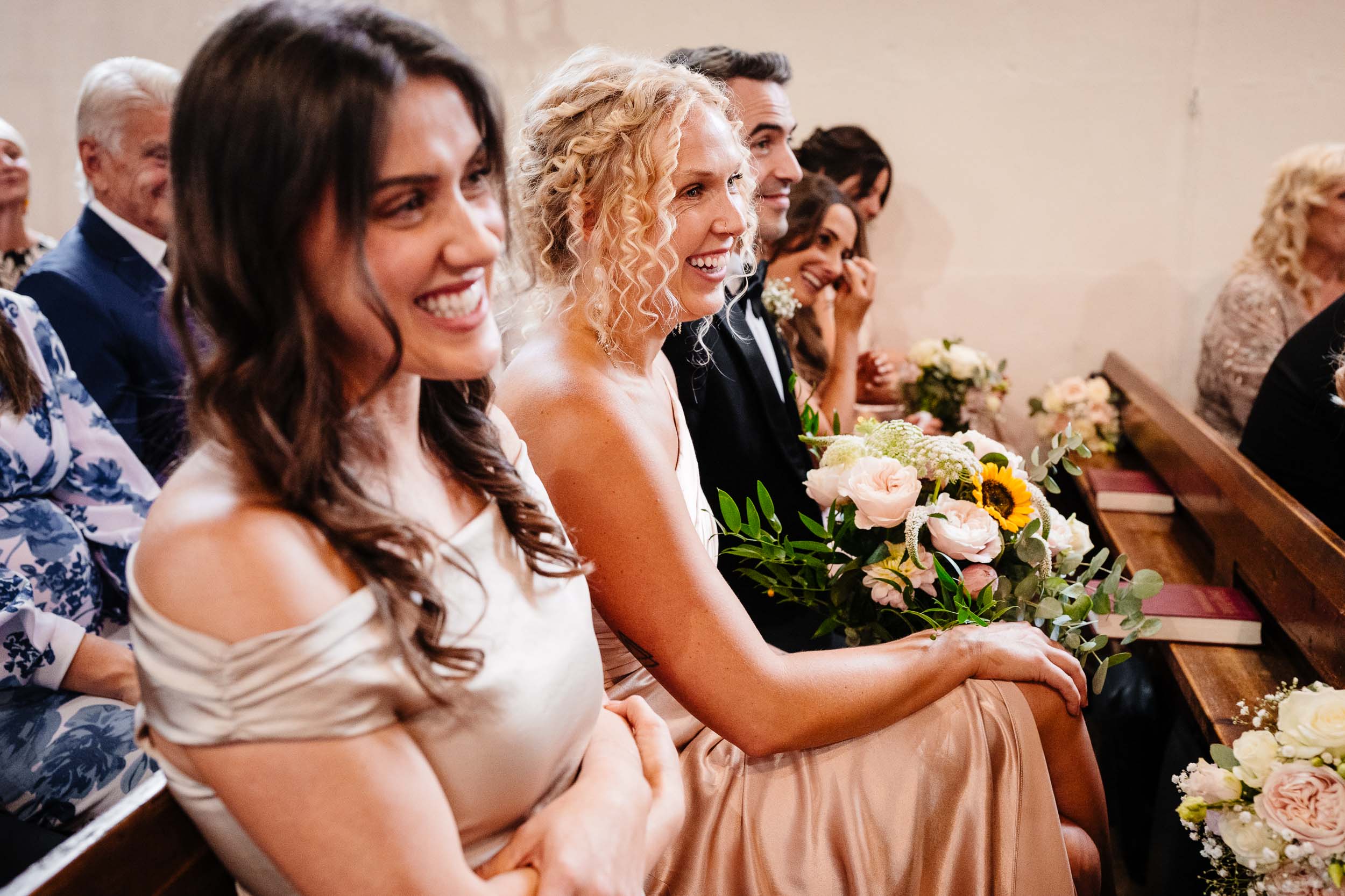 Bridesmaids and guests laughing during the ceremony