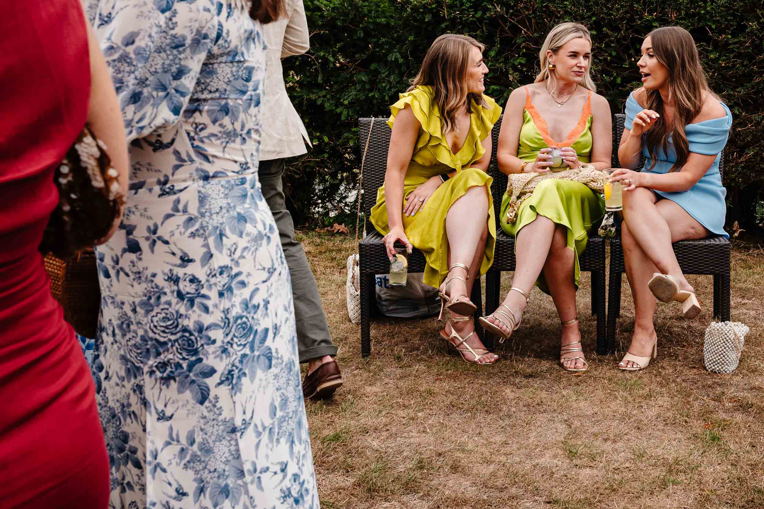 Wedding guests sitting on chairs wearing colourful dresses