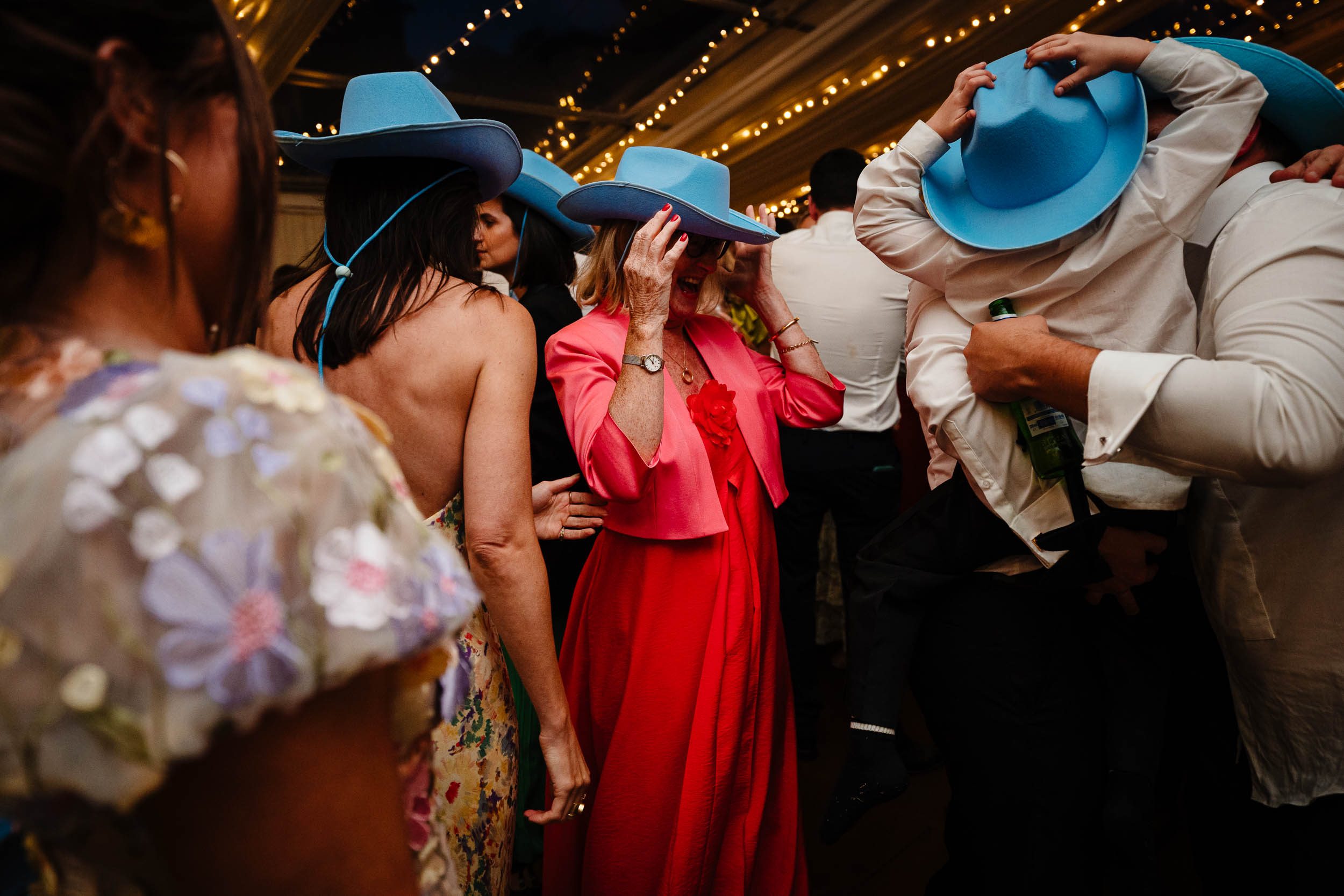 Colourful dance floor photo with a guest in a red dress and blue hat