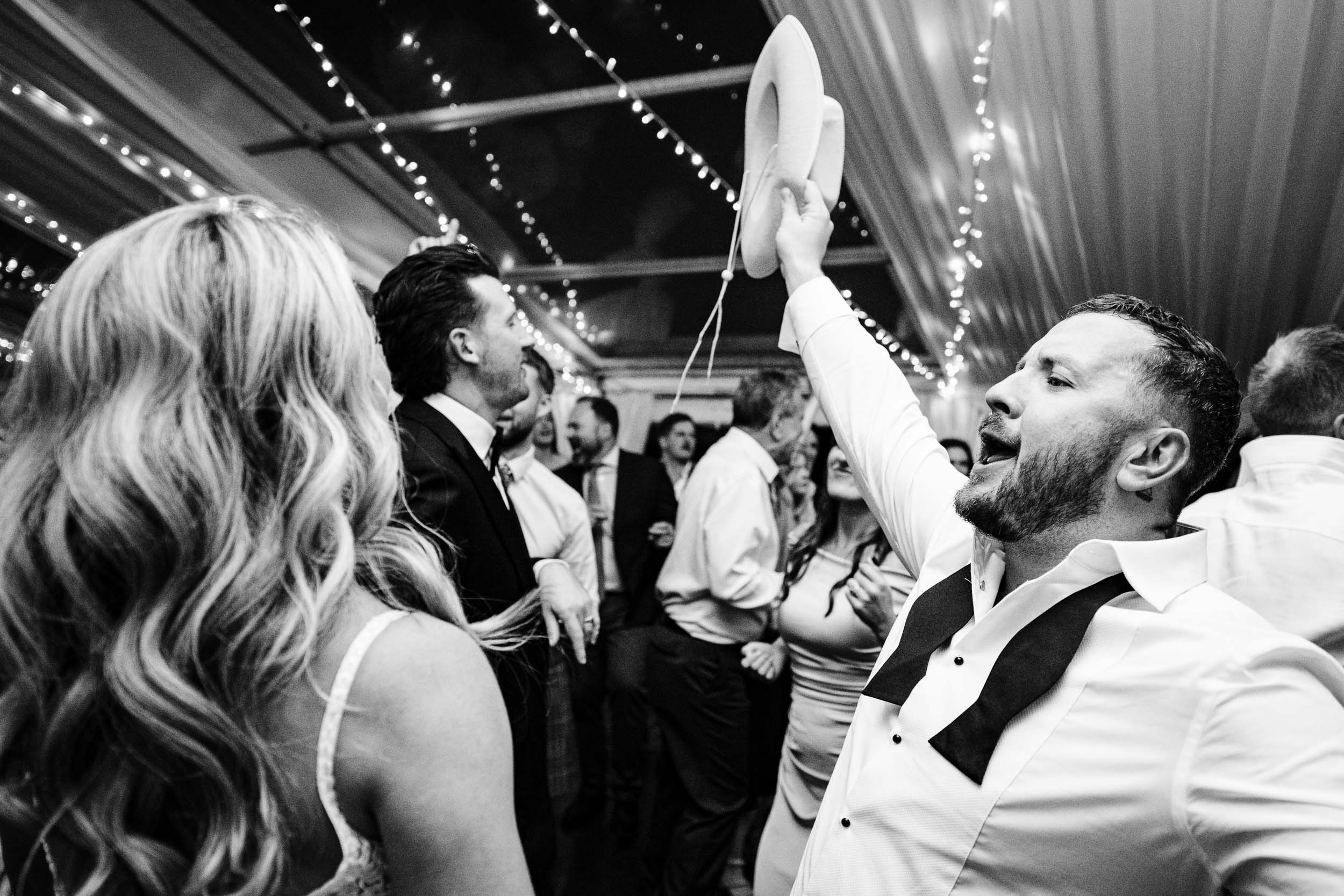 Groom taking his hat off and cheering during the party