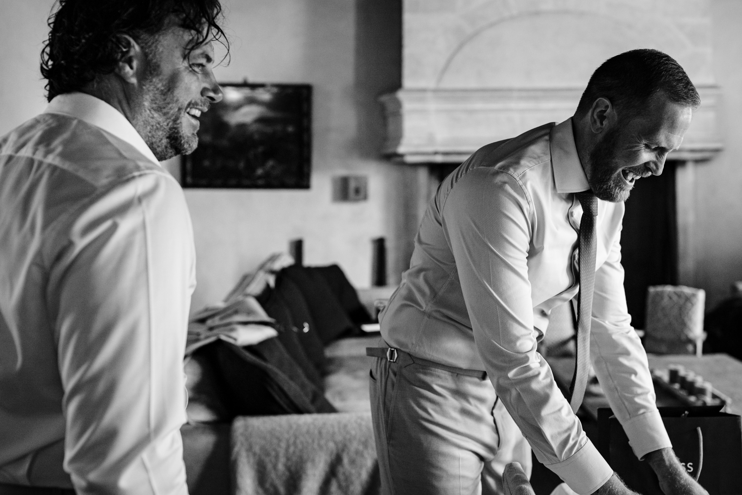 Groom and best man laughing together while getting ready