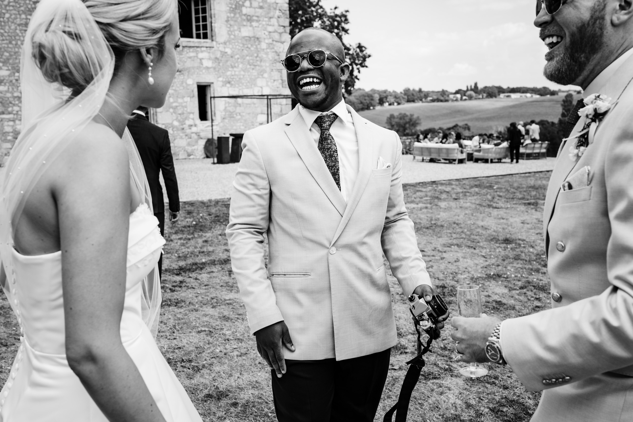 Bride and groom laughing while chatting with a wedding guest during the drinks reception