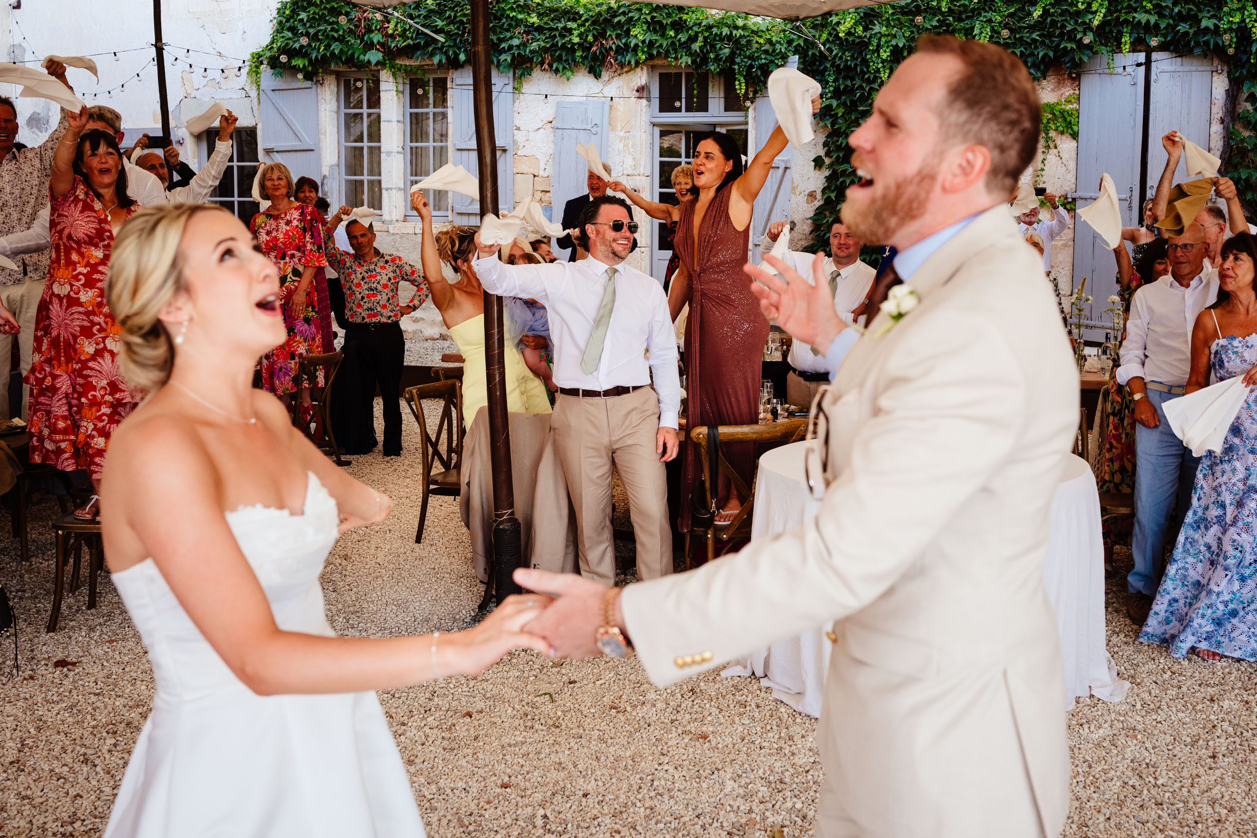 Bride and groom making their entrance into the dining area as guests wave napkins in the background