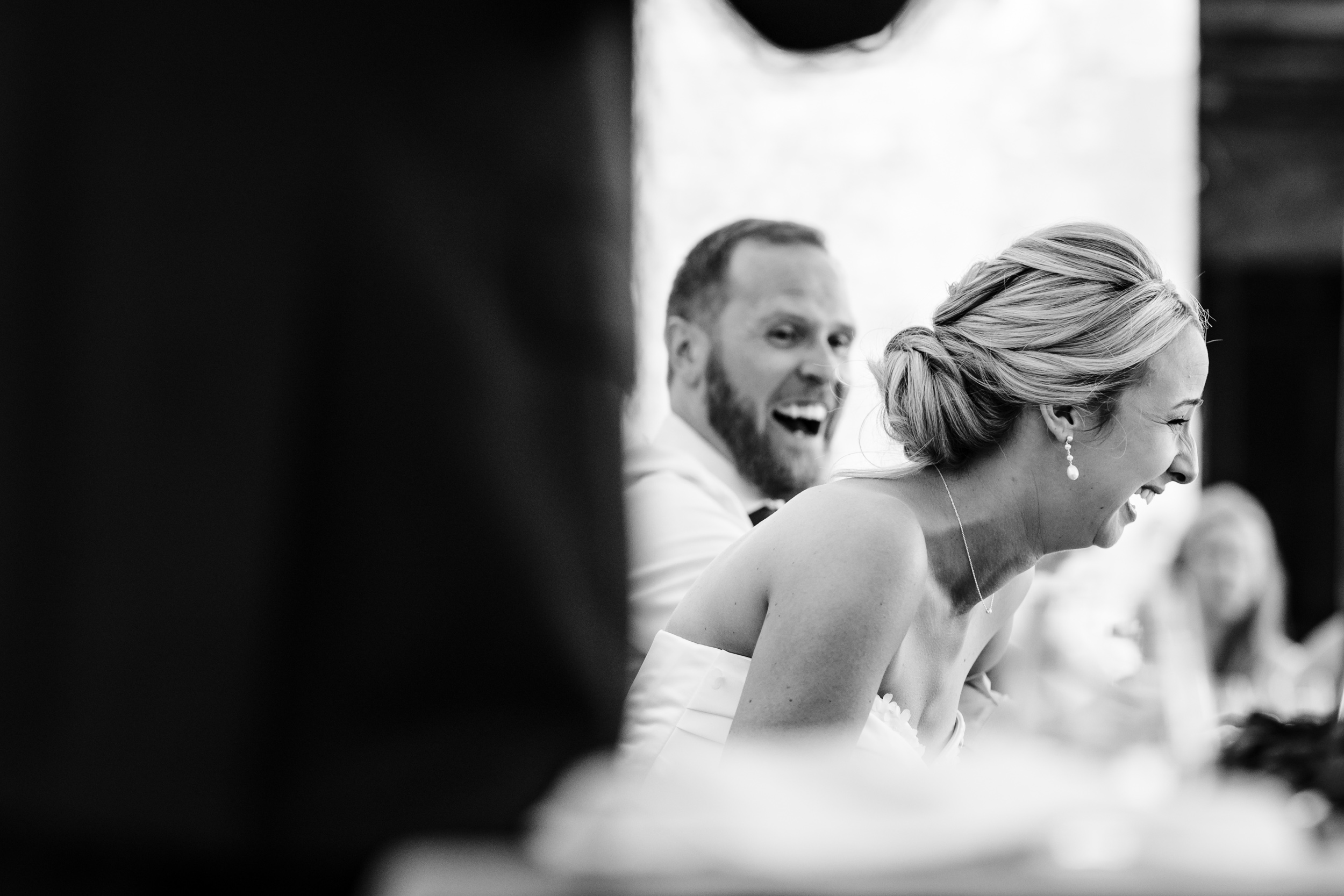 Bride and groom bursting out laughing together during the speeches