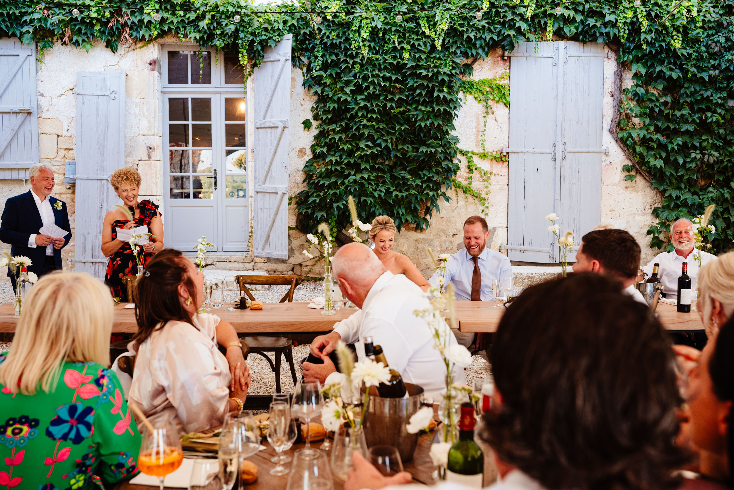 Wide view of the top table during the speeches with guests laughing and enjoying the moment