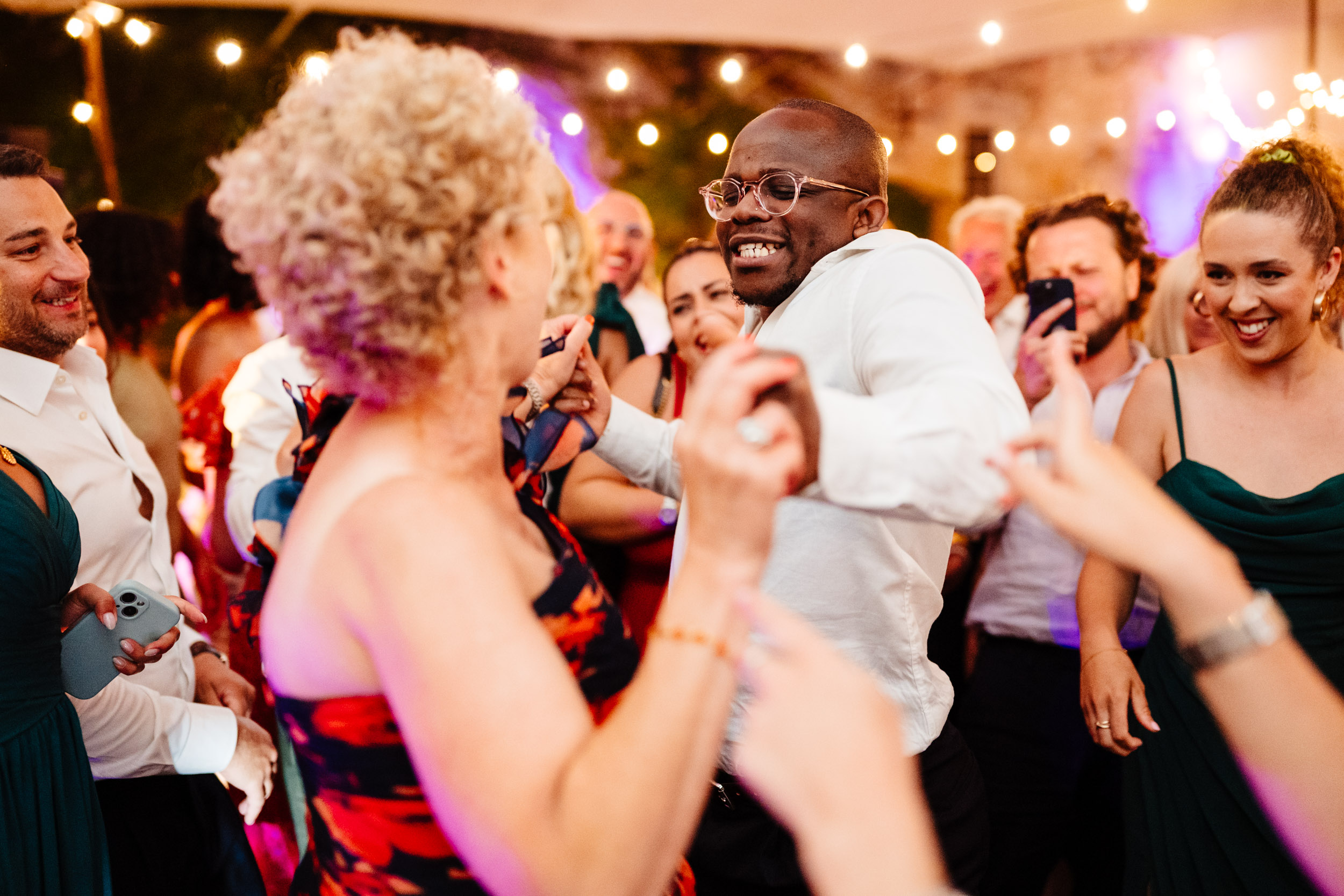 Wedding guests dancing energetically on the dance floor as the evening begins